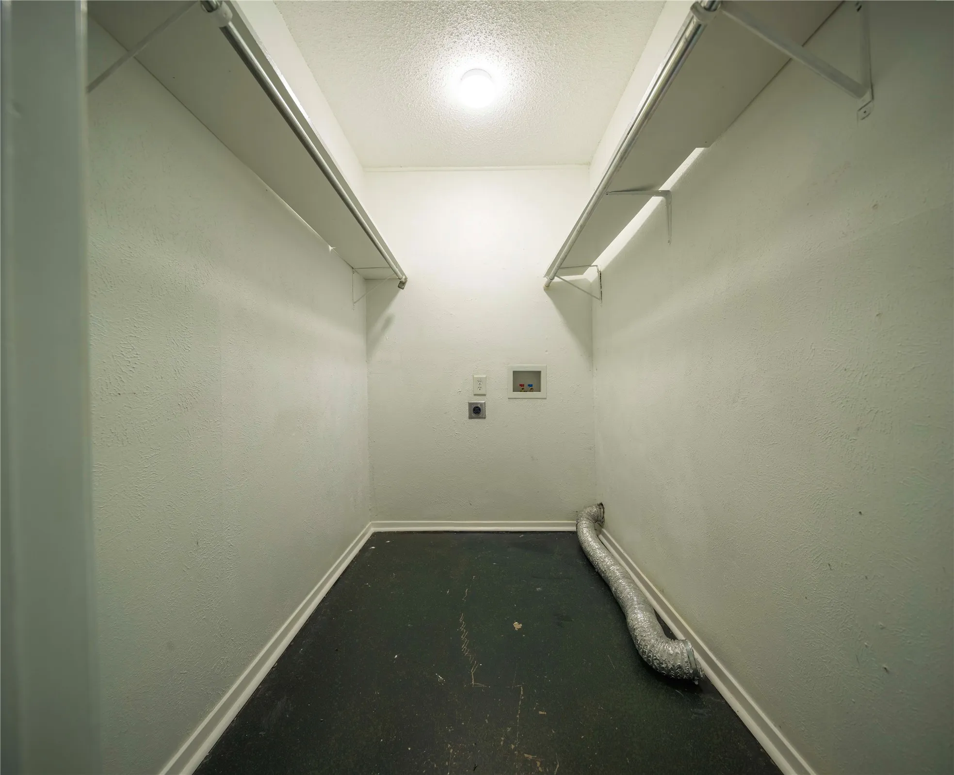 Dedicated utility area with appliance hookups, overhead lighting, and integrated shelving