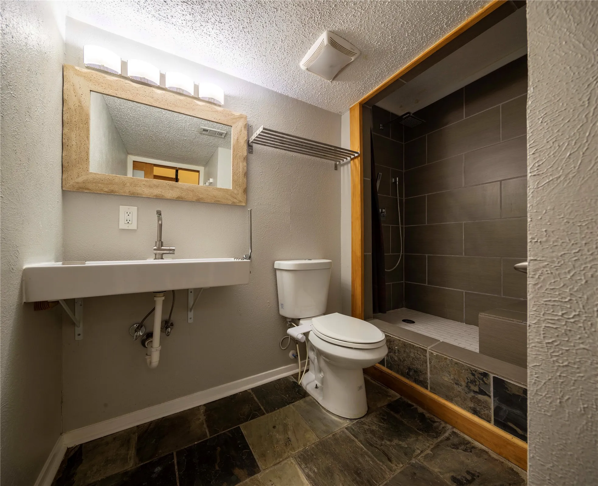 Walk-in shower with dark gray tile surround and built-in bench