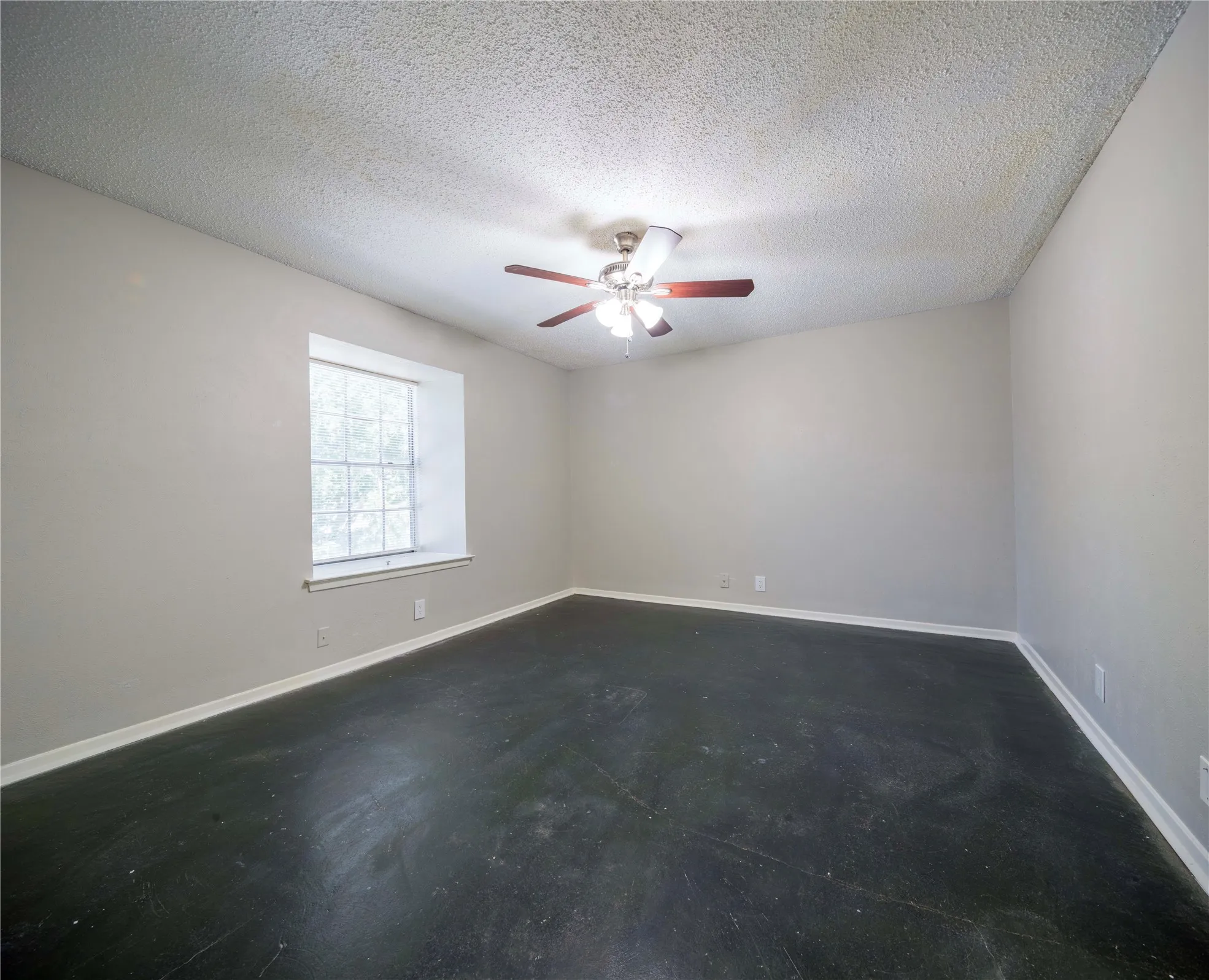 Neutral wall paint with textured ceiling, ceiling fan with light fixture, and window with white trim