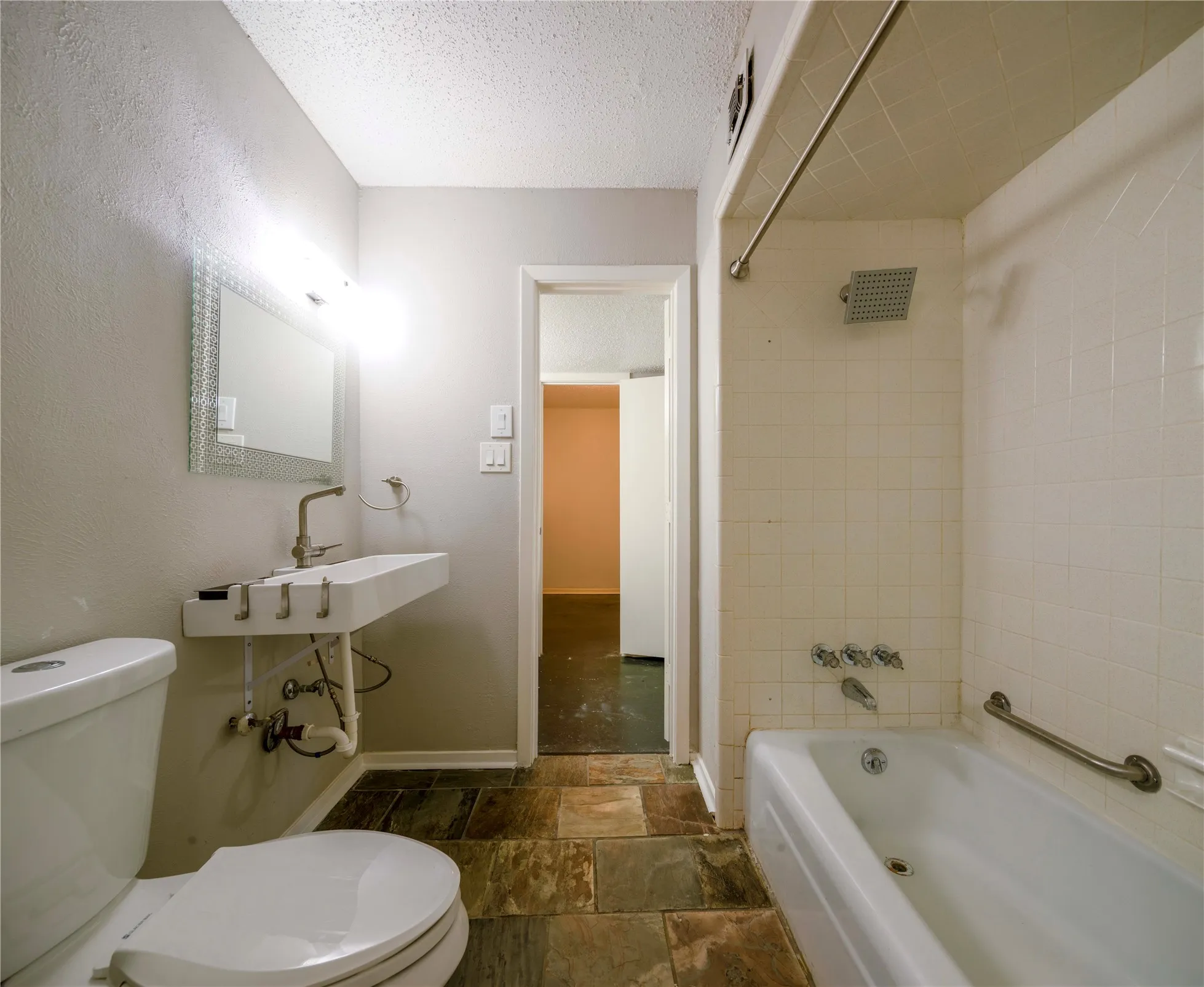 Rectangular vessel sink with wall-mounted faucet, mosaic-framed mirror, and a full bathtub with a rain shower head