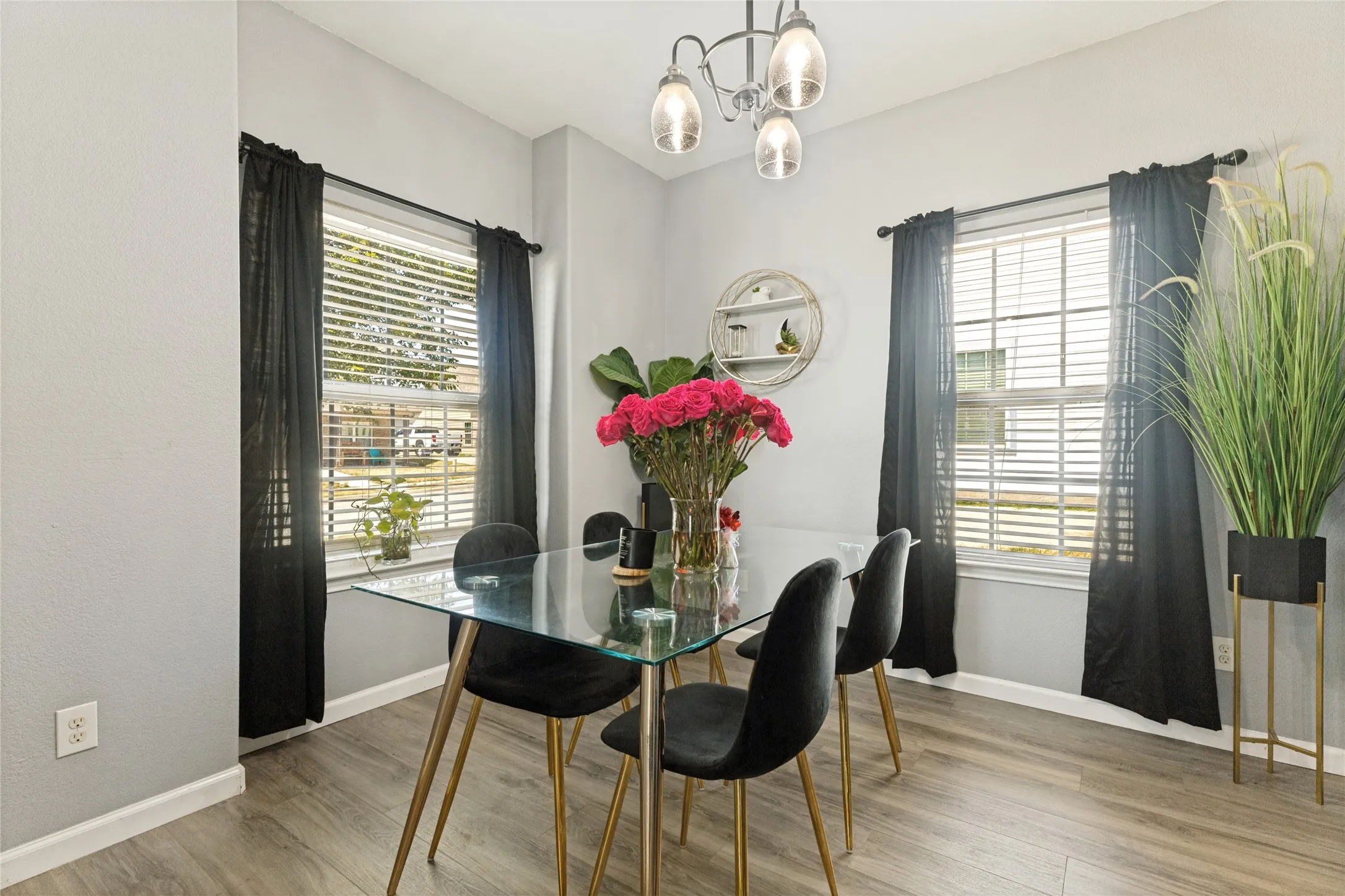 Wood-finish flooring, two large windows with blinds, and an overhead multi-bulb light fixture