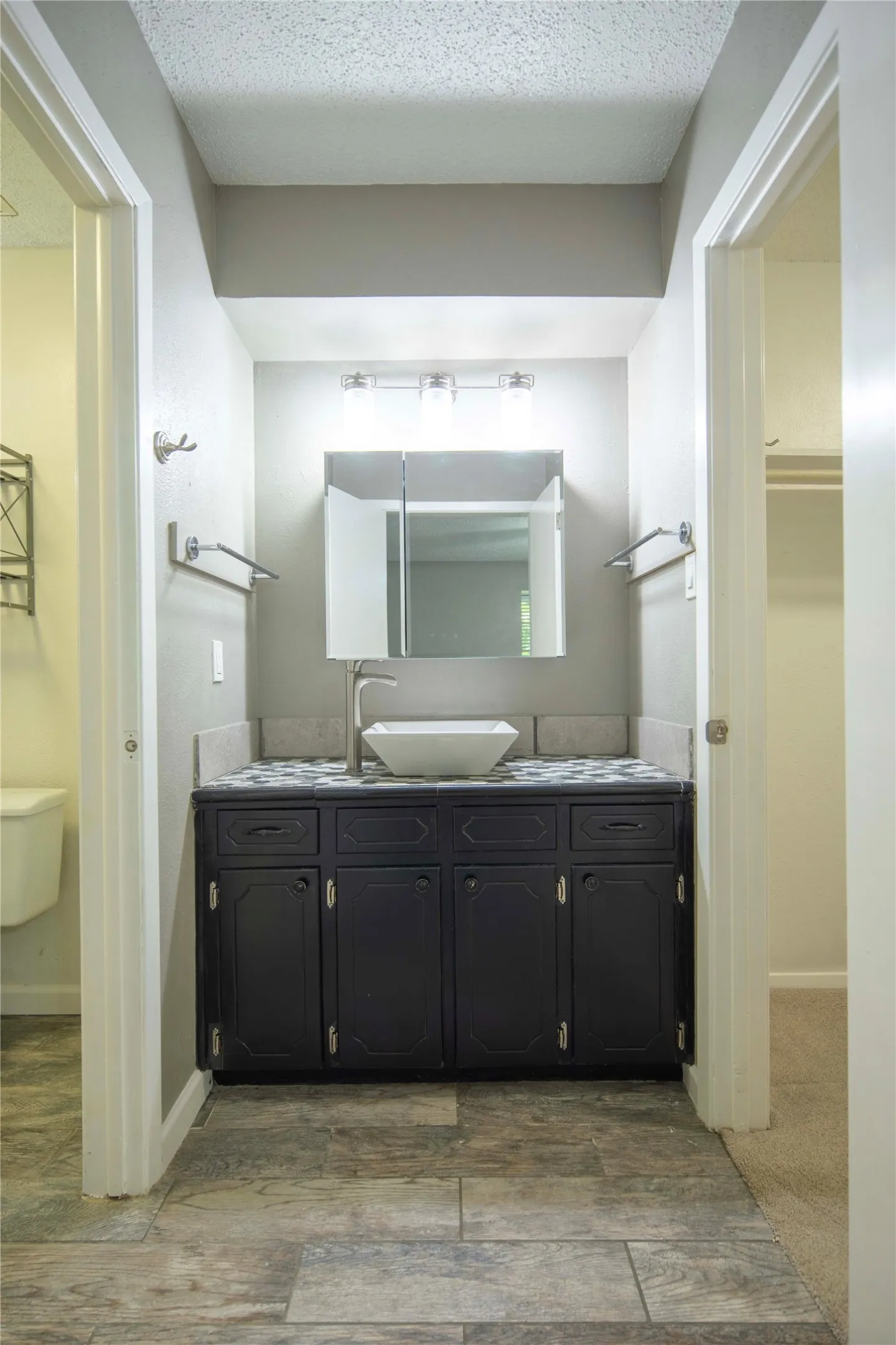 Vanity with dark cabinetry and a vessel sink, complemented by a mosaic tile countertop