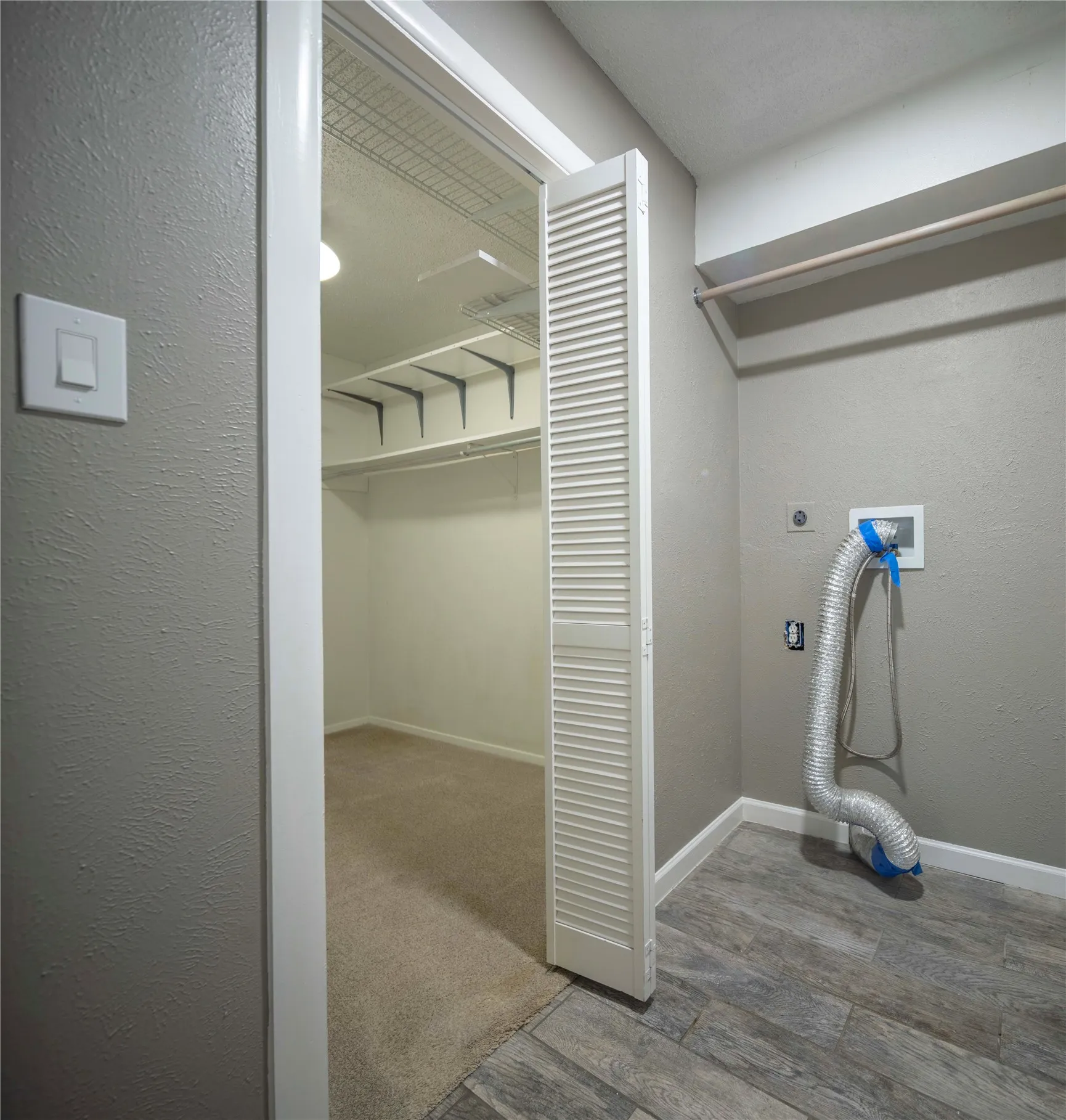 Laundry area with wood-finish flooring, a wall-mounted drying rod, and utility hookups