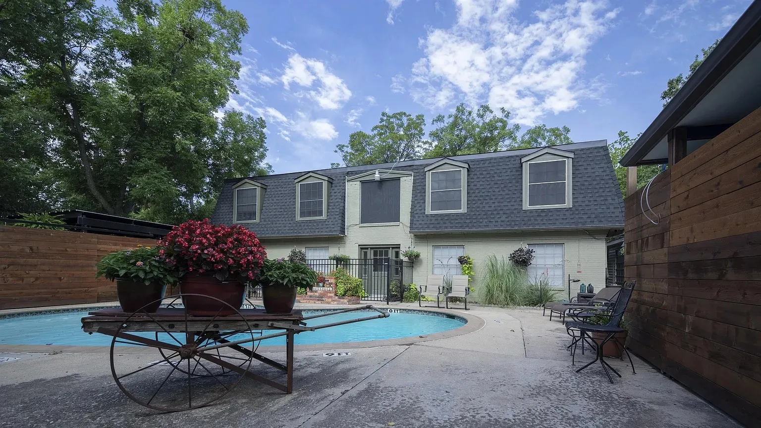 Swimming pool with concrete surround, surrounded by a wood-paneled privacy fence