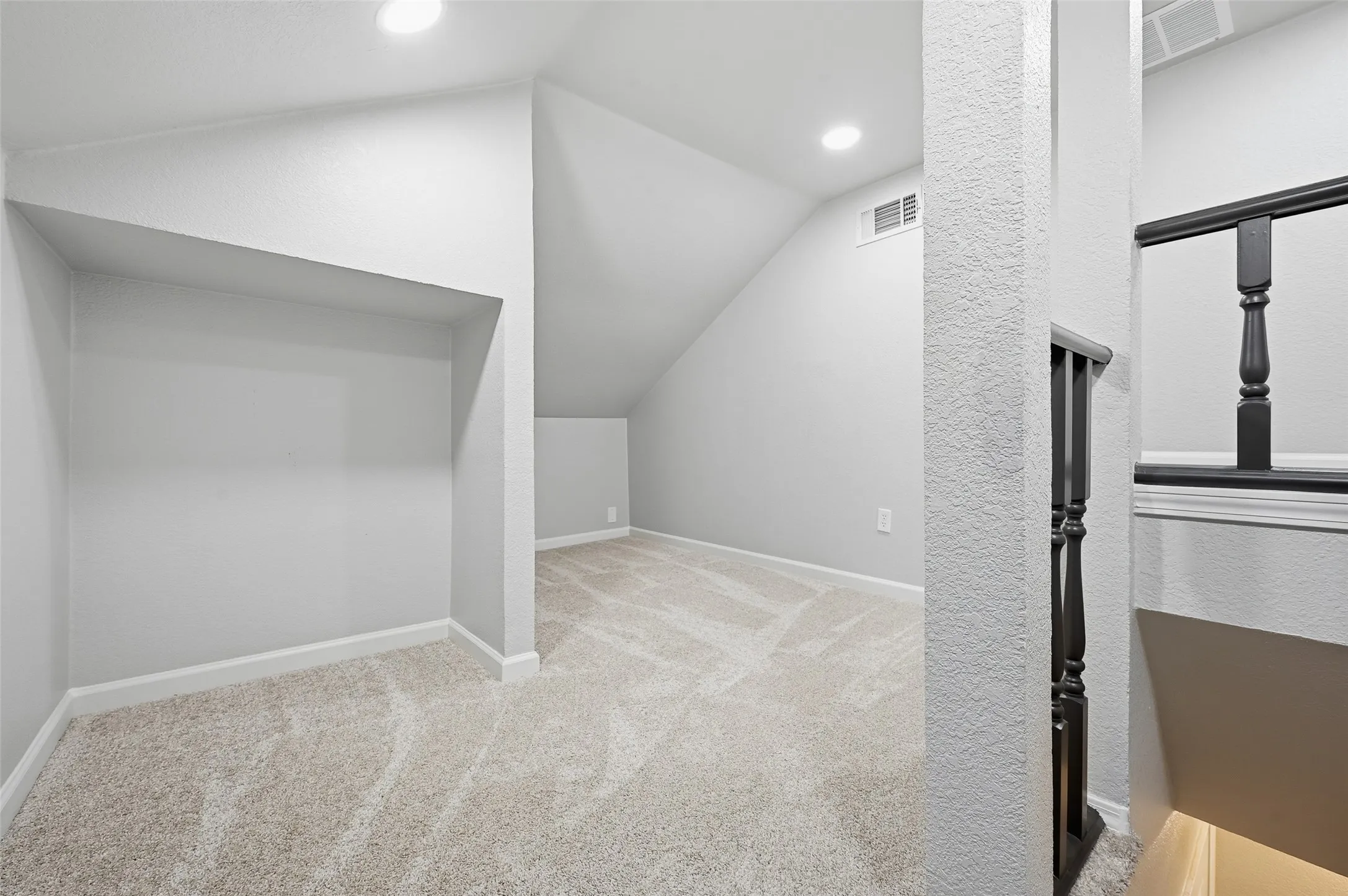 Carpeted upper level with recessed lighting and sloped ceilings
