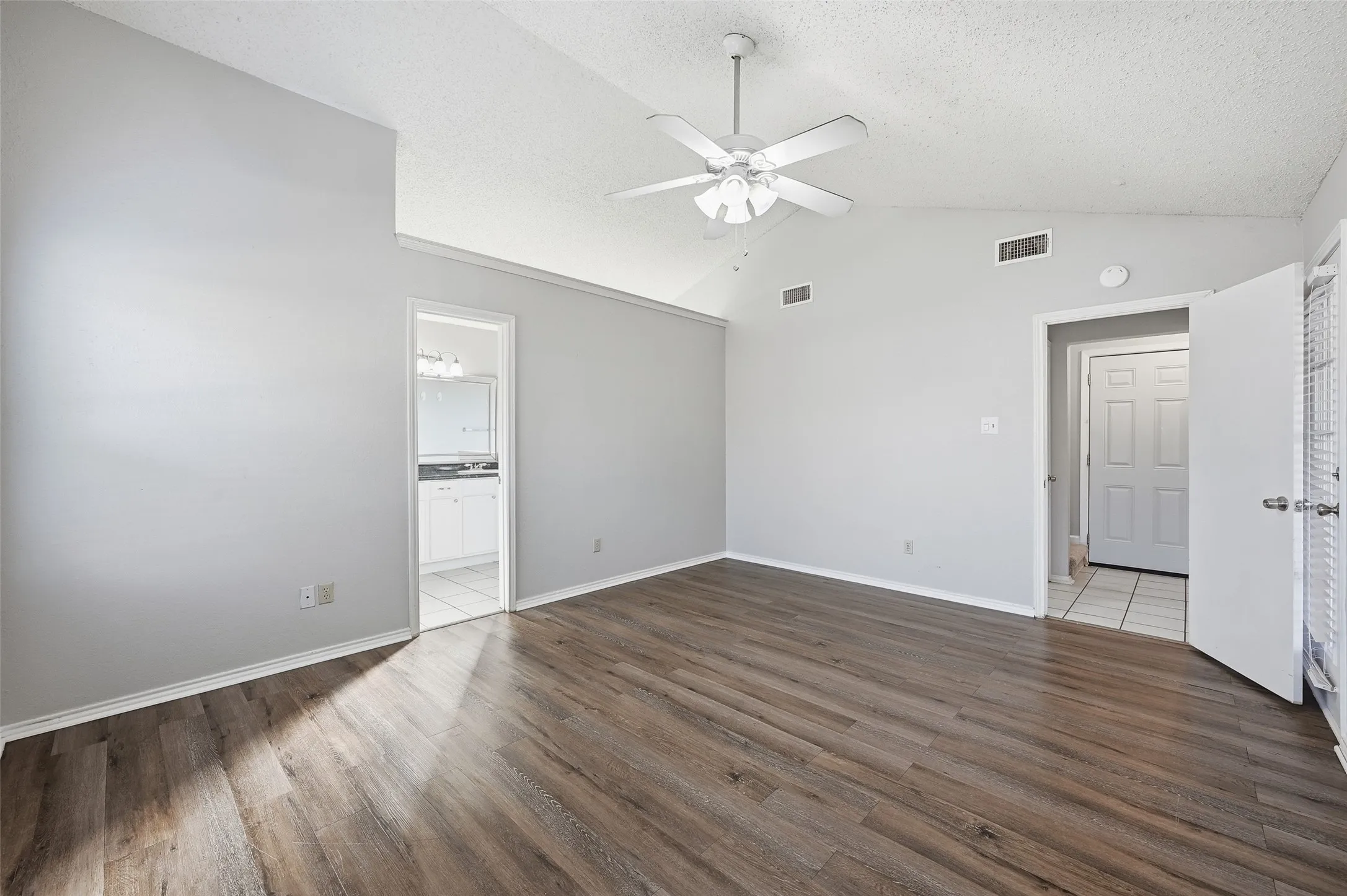 Vaulted ceiling with a ceiling fan, wood-finish flooring, and light gray wall paint