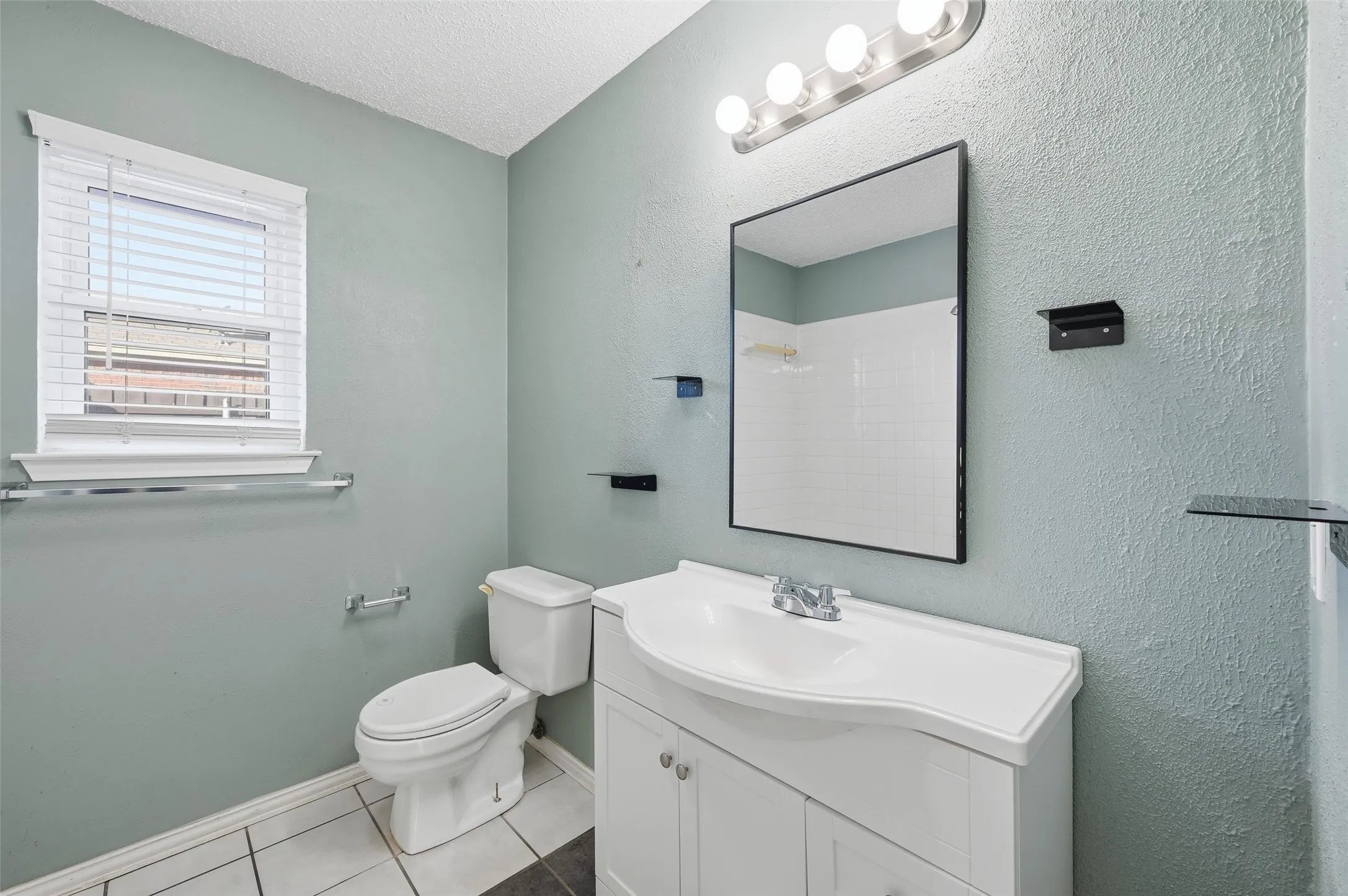 White vanity with integrated sink, rectangular mirror, and overhead vanity lighting