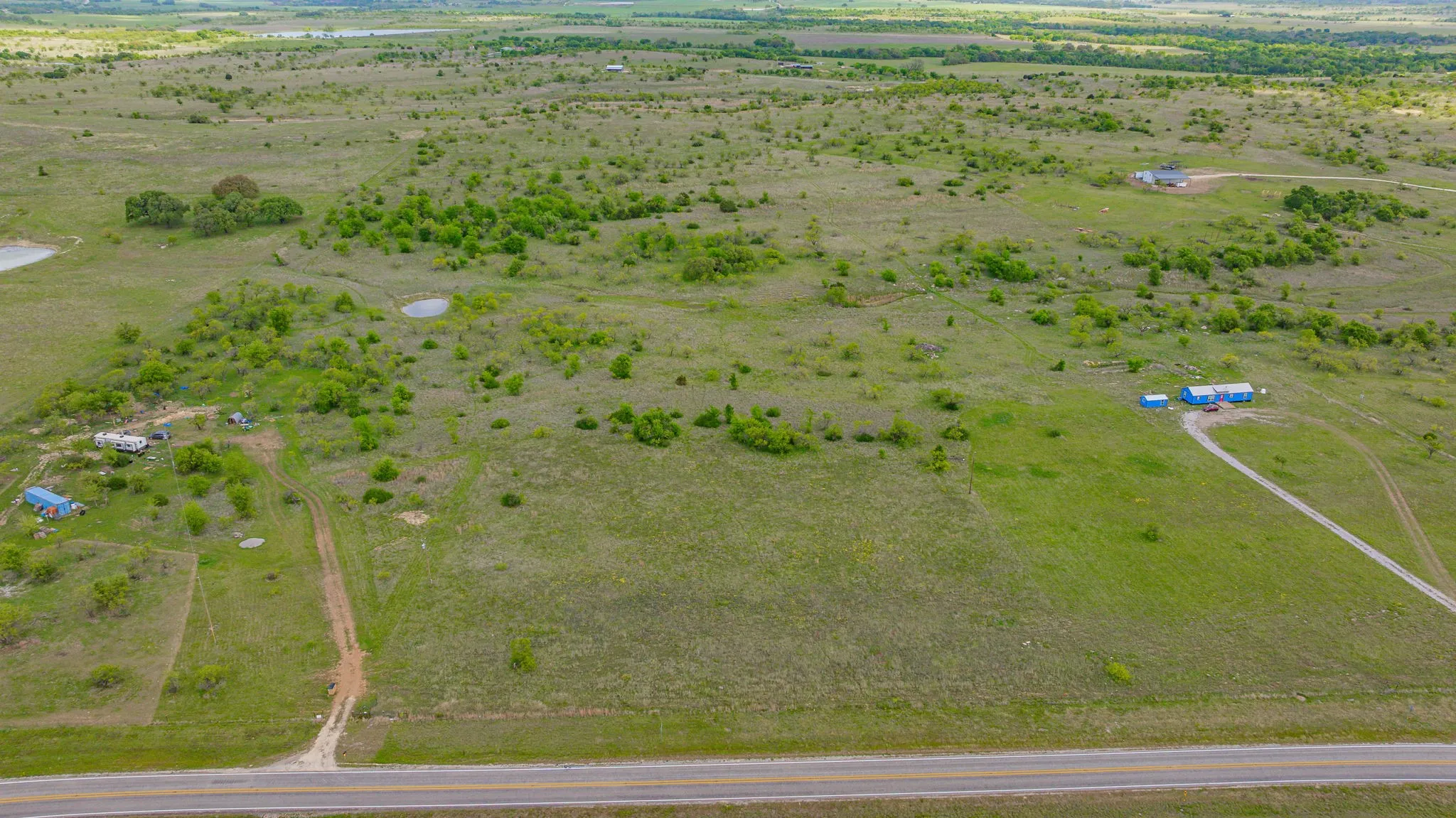 Expansive rural property featuring open grasslands, scattered mature trees, and multiple small ponds