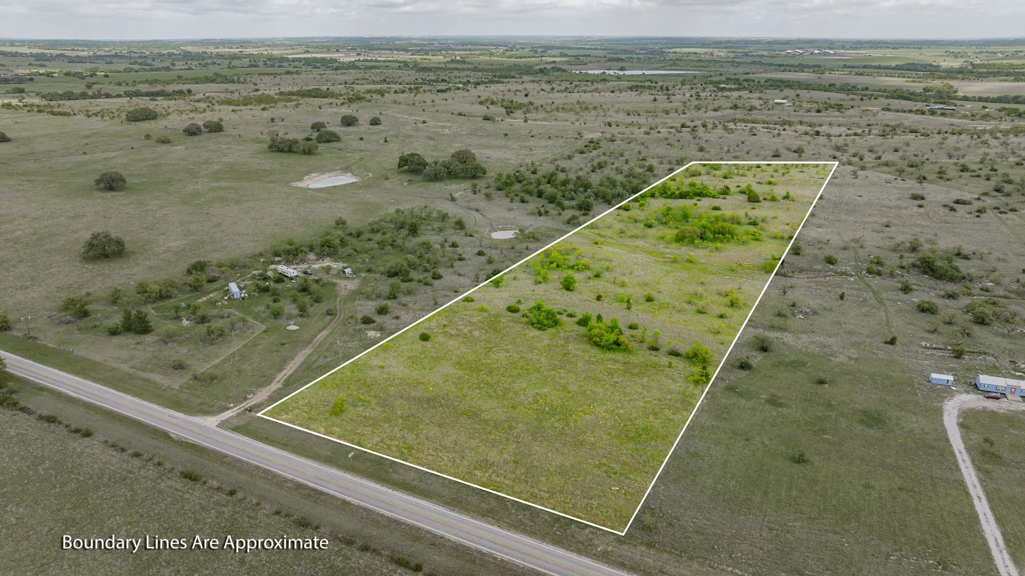Expansive land parcel featuring a road frontage, varied terrain, and scattered natural vegetation
