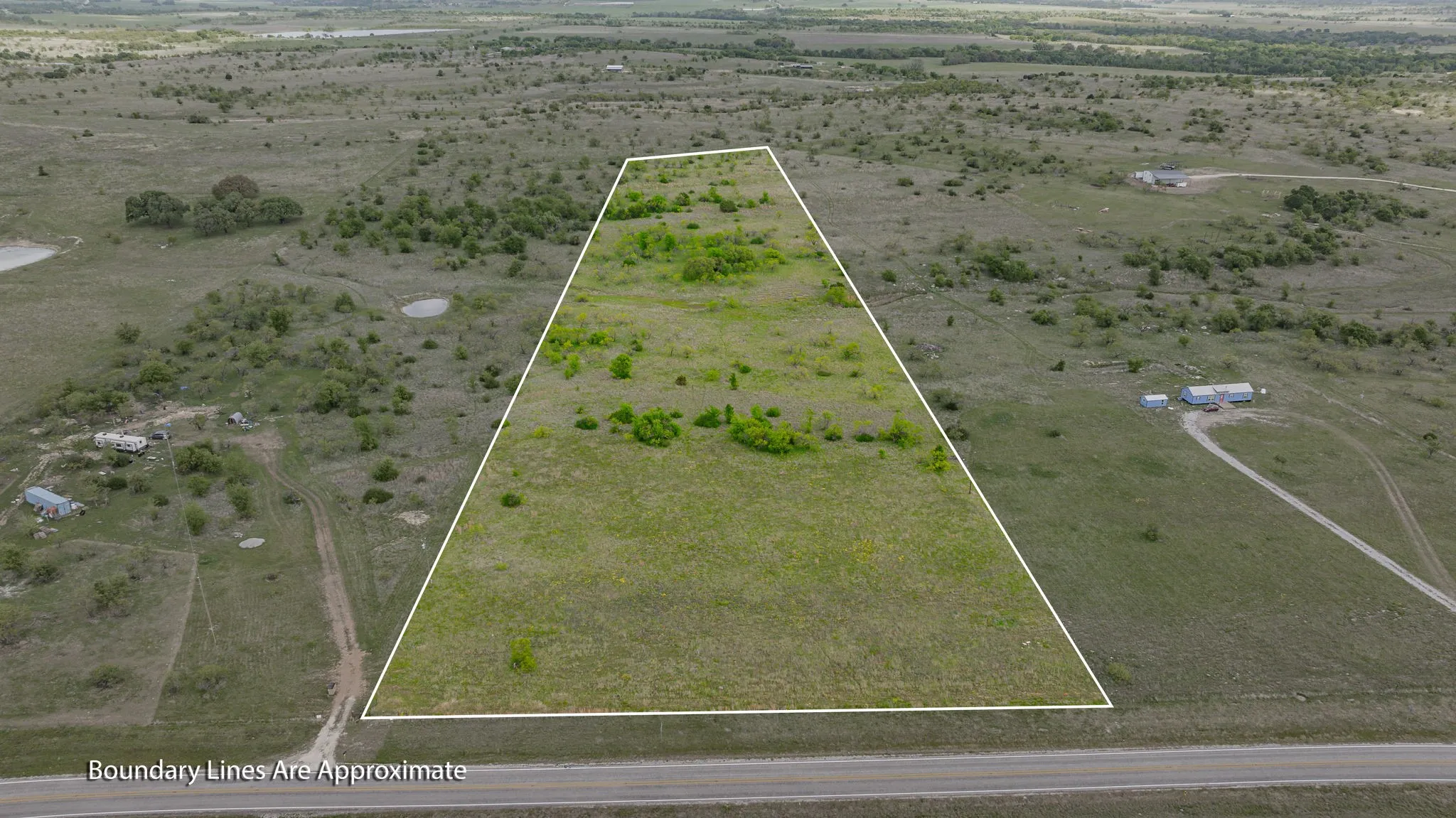 Expansive undeveloped land with natural vegetation and visible road access