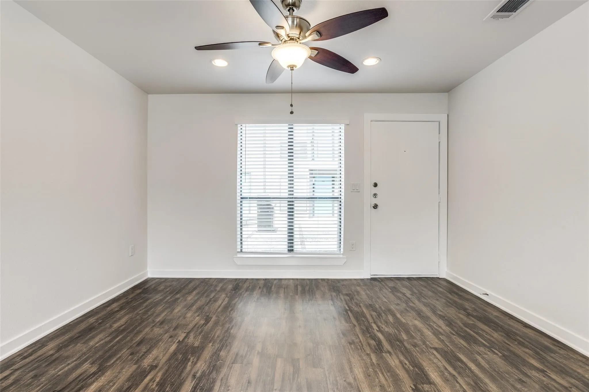 Wood-finish flooring, ceiling fan with integrated lighting, recessed lighting, white interior door, and window with blinds
