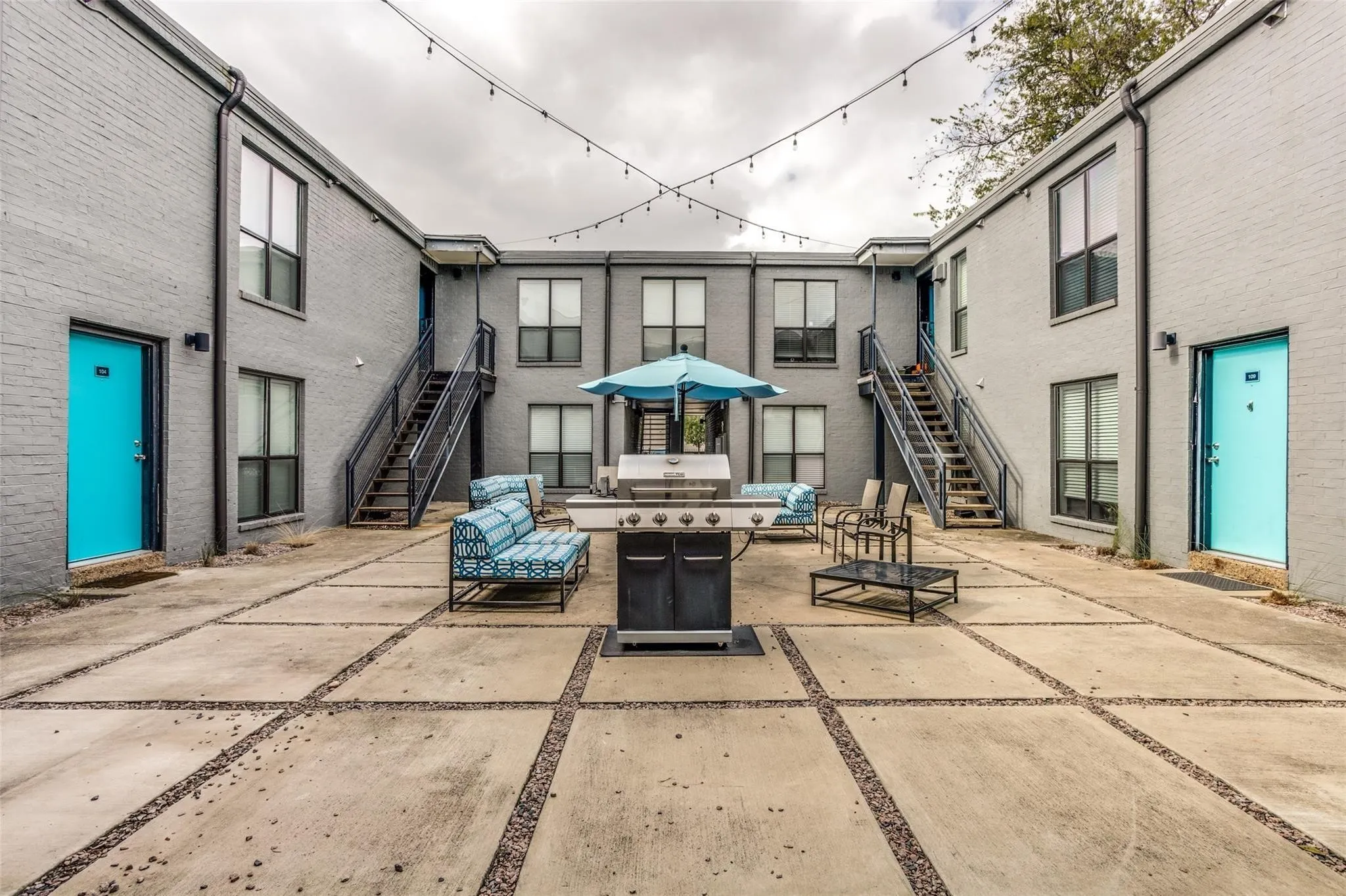Central courtyard with concrete paving, string lighting, and exterior staircases providing access to upper levels