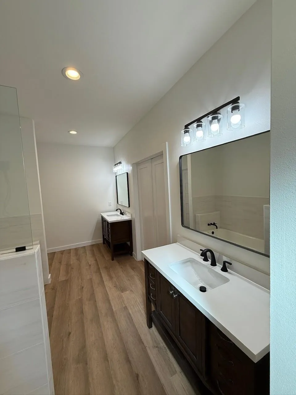 Dual dark wood vanities with white countertops, undermount sinks, and matte black fixtures