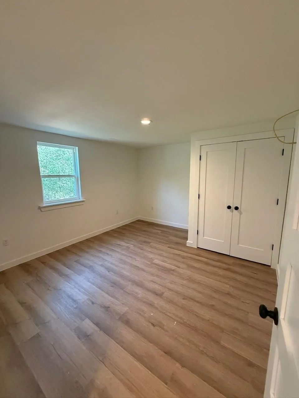 Recessed ceiling lighting, wood-finish flooring, white trim, and a built-in closet with double doors