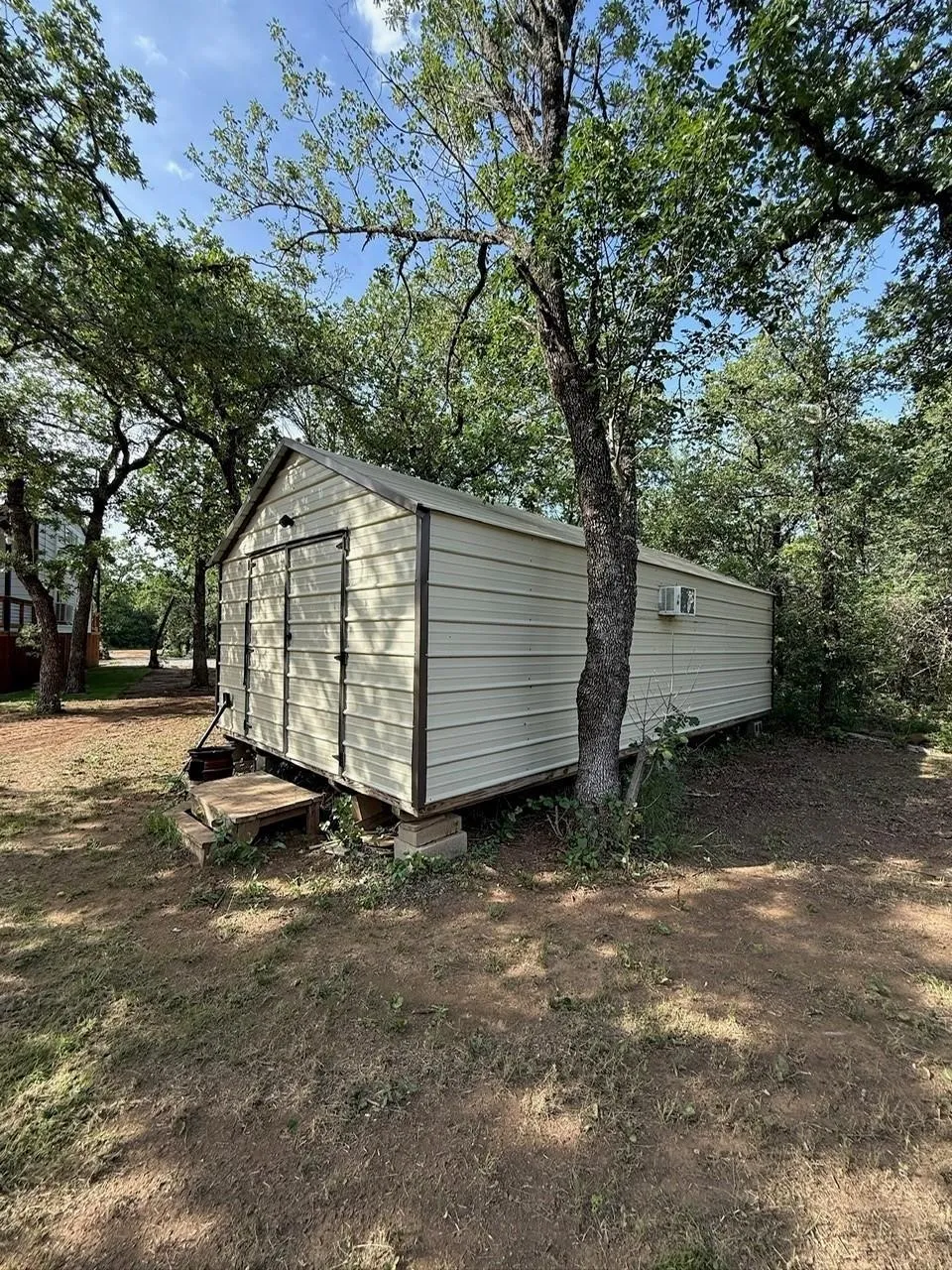 Metal storage shed with a gable roof, double front doors, and a side-mounted air conditioning unit