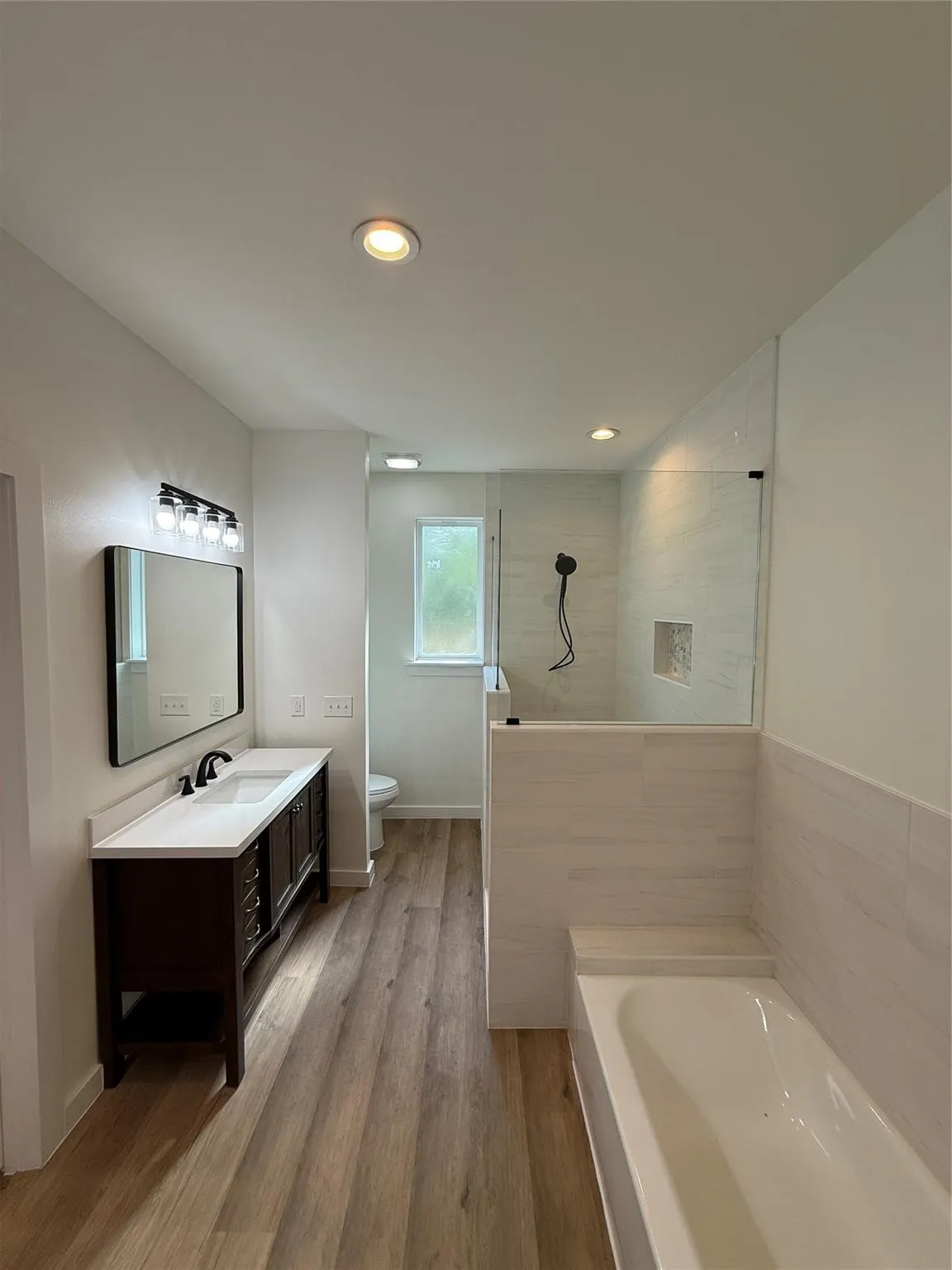 Walk-in shower with clear glass enclosure and tiled niche