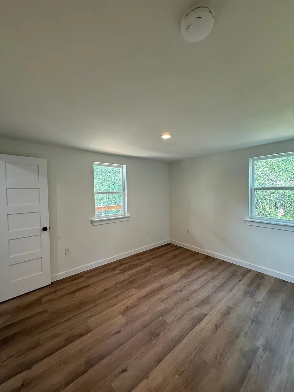 Hardwood-style flooring, white trim, recessed lighting, and white paneled door