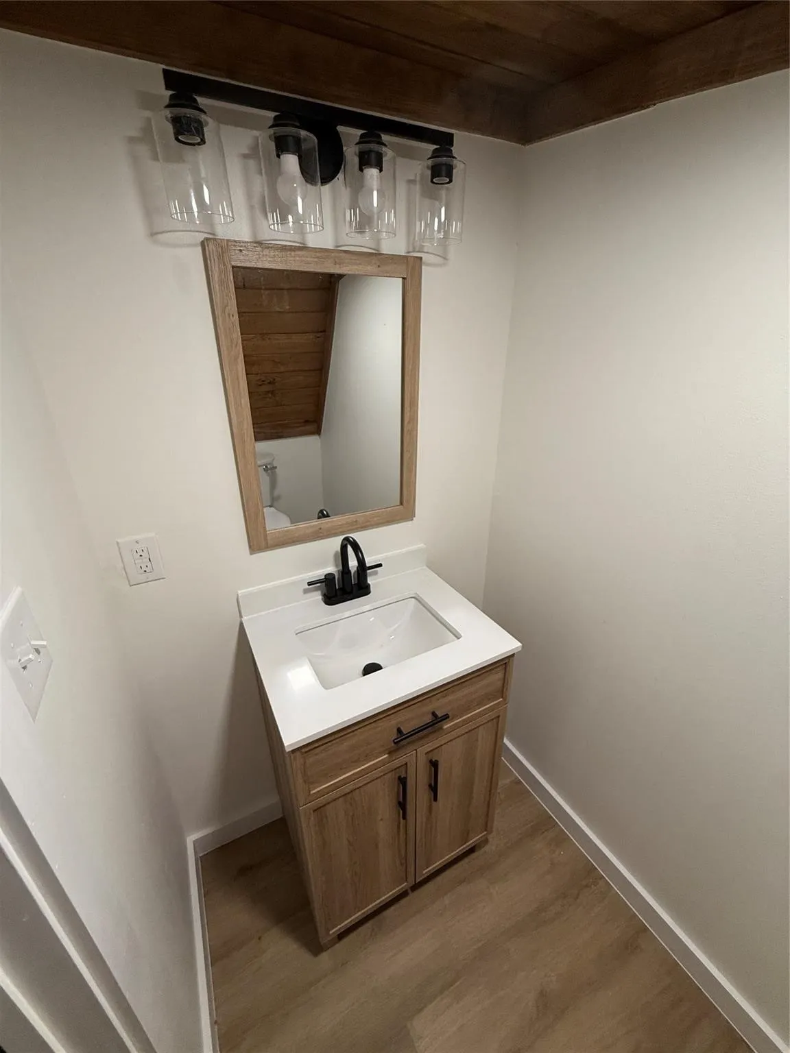 Vanity featuring wood-finish cabinetry, white countertop, and a black faucet