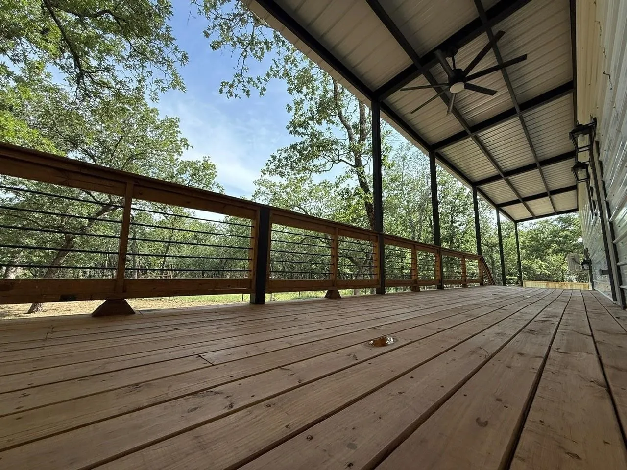 Expansive wood deck with cable railing system, metal roof, and ceiling fan
