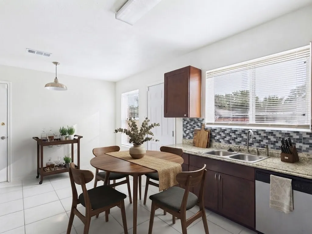 White tile flooring, dual-basin stainless steel sink, wood-finish cabinetry, mosaic tile backsplash, and light-toned countertop