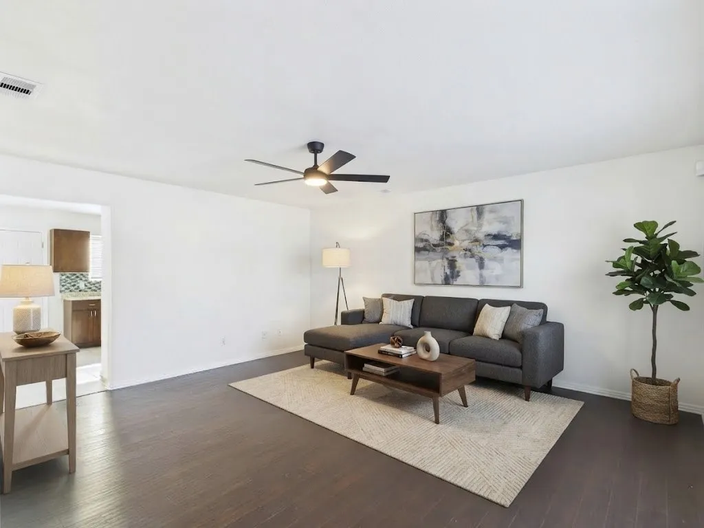 Expansive living area with wood-finish flooring, a contemporary ceiling fan, and recessed lighting