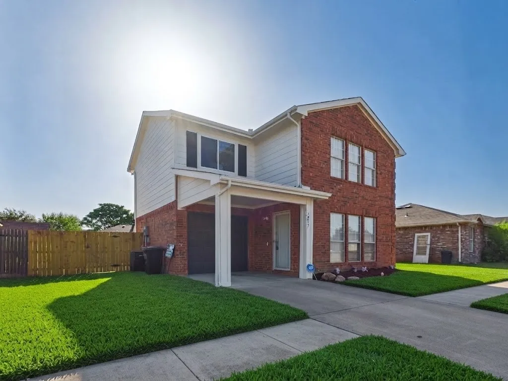 Brick and siding exterior with a covered entry, established landscaping, and a fenced yard
