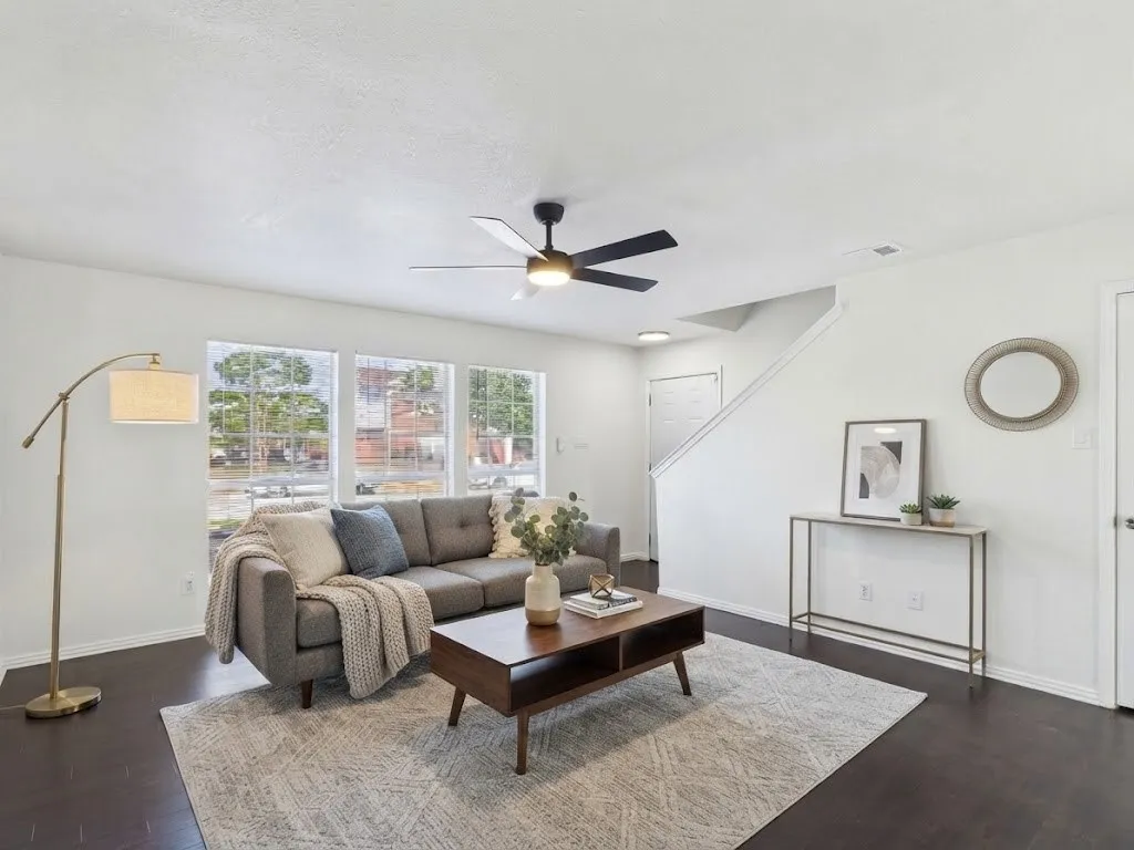 Dark wood-finish flooring, white walls, multiple windows, recessed lighting, and a ceiling fan with integrated lighting