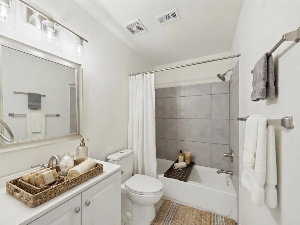White vanity cabinetry with brushed nickel hardware, a white countertop, and a rectangular mirror