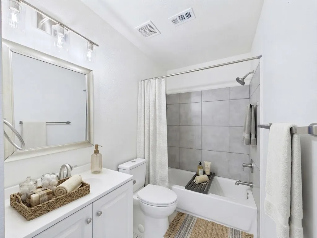White vanity with integrated sink, rectangular framed mirror, and brushed nickel light fixture