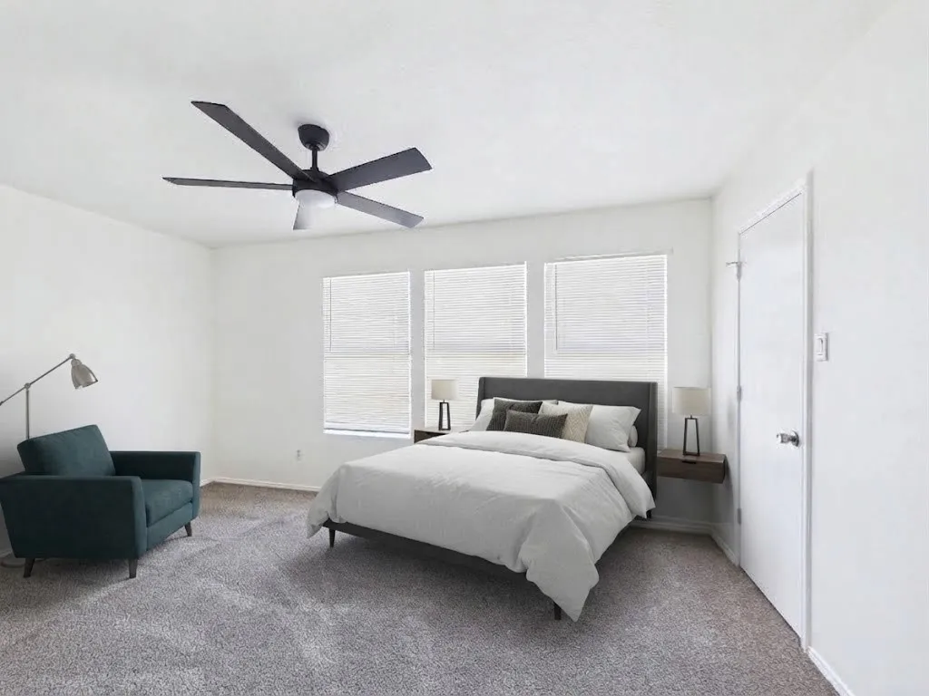 Gray plush carpeting, ceiling fan with integrated lighting, multiple windows with blinds, and a white interior door