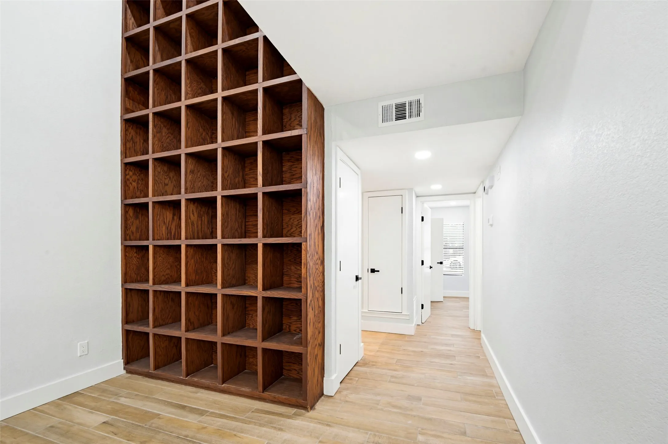 Built-in wood-finish shelving, wood-finish flooring, recessed lighting, and white panel doors with black hardware