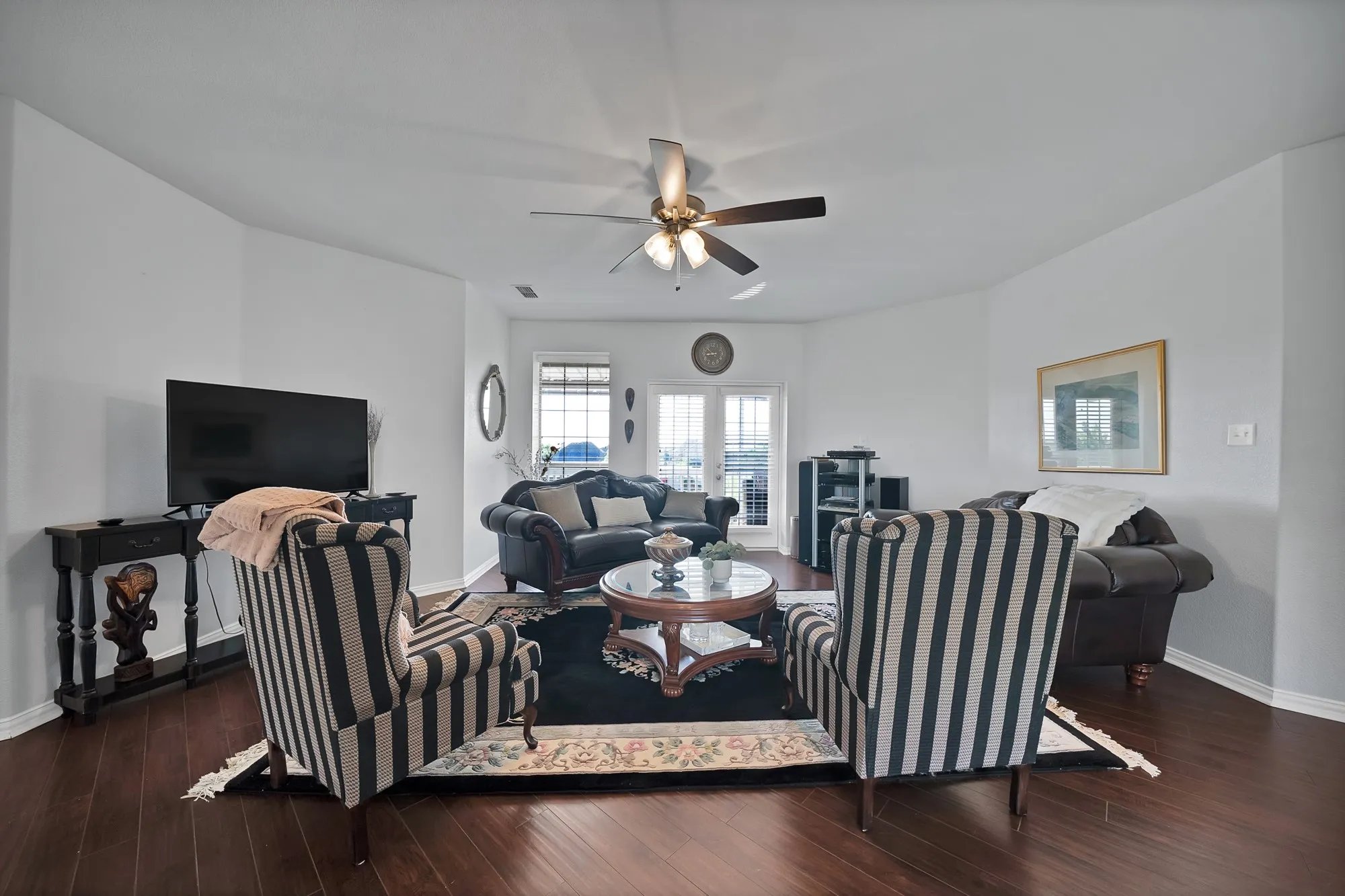 Upper-level living area, third angle — Dark hardwood floors, ceiling fan, French doors with rear-facing windows, and open layout suitable for second living room, game room, or media room use.