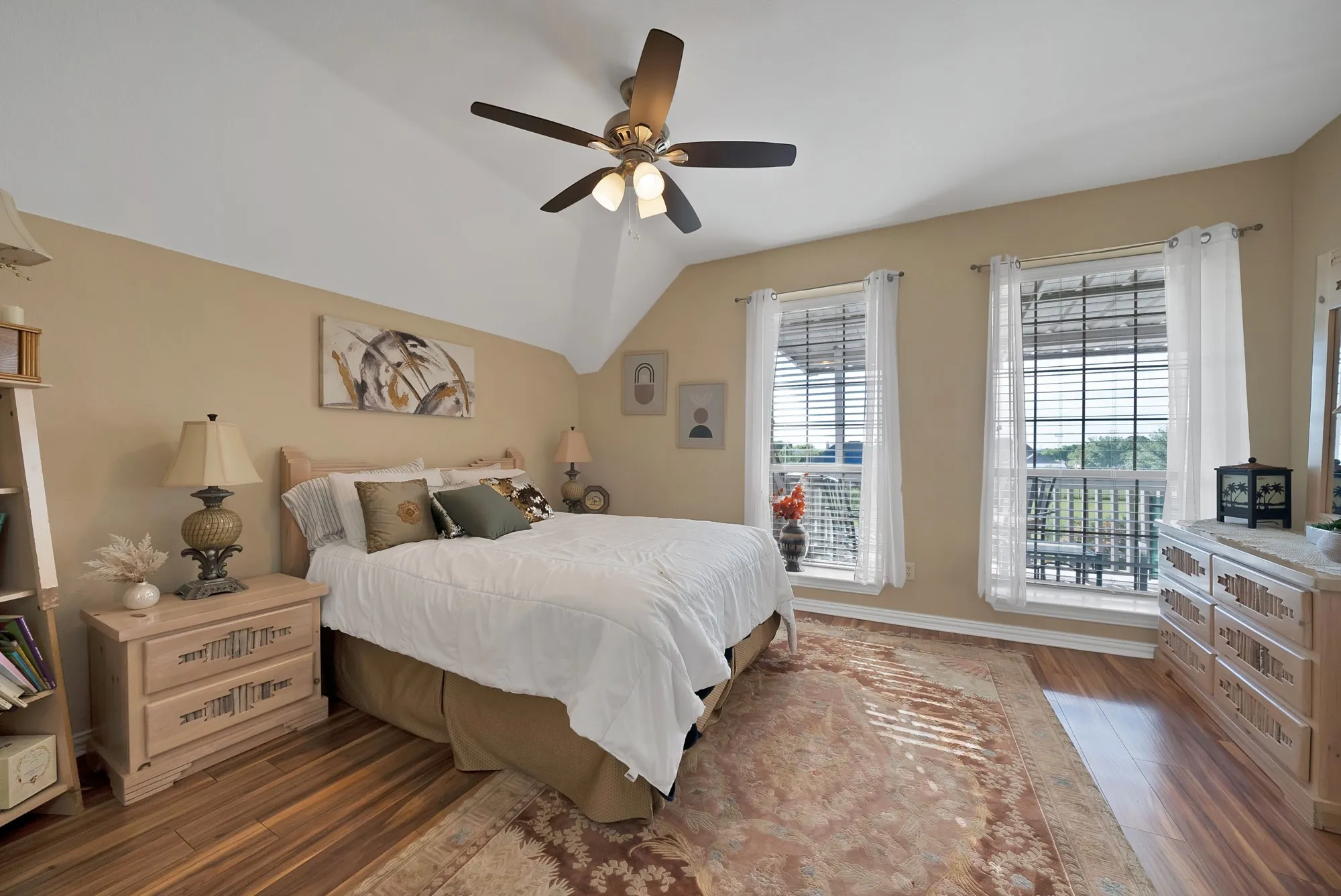 Secondary bedroom, with vaulted ceiling — Vaulted ceiling with ceiling fan, dark hardwood floors, dual windows with rear-facing views, and room size accommodating a queen bed with sitting area.