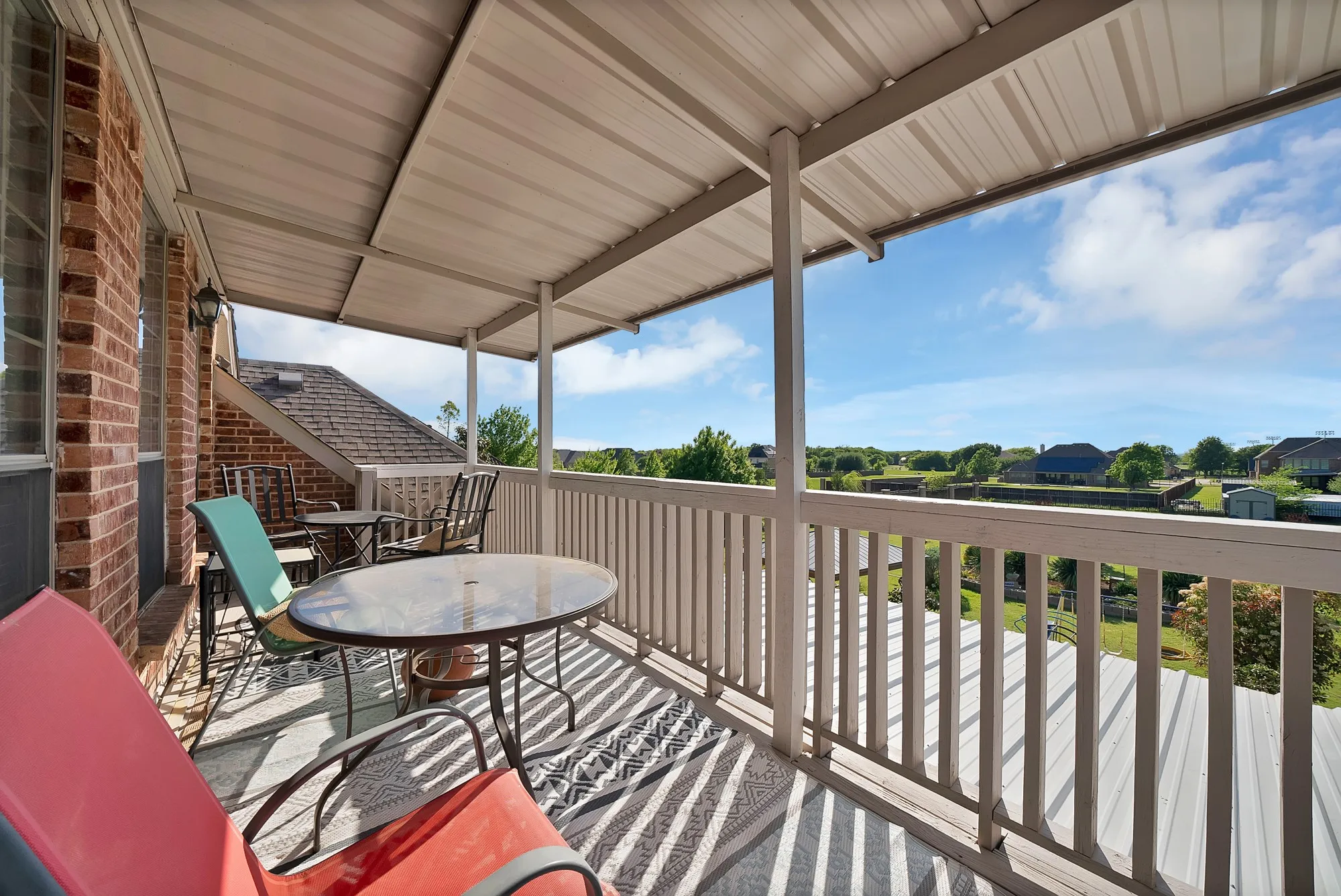 Upper-level covered balcony — Covered balcony with metal panel ceiling, wood post construction, wood deck flooring, and open rear yard views. Accessible from upper-level living area.