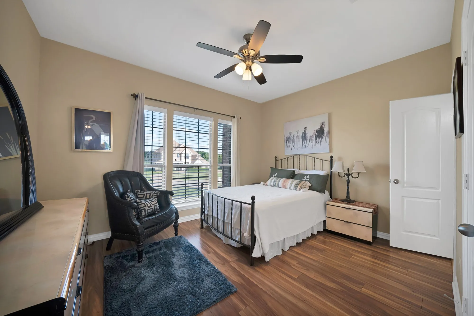 Secondary bedroom, upper level — Dark hardwood floors, ceiling fan, double window with rear yard view, and standard closet. Room accommodates full or queen bed.