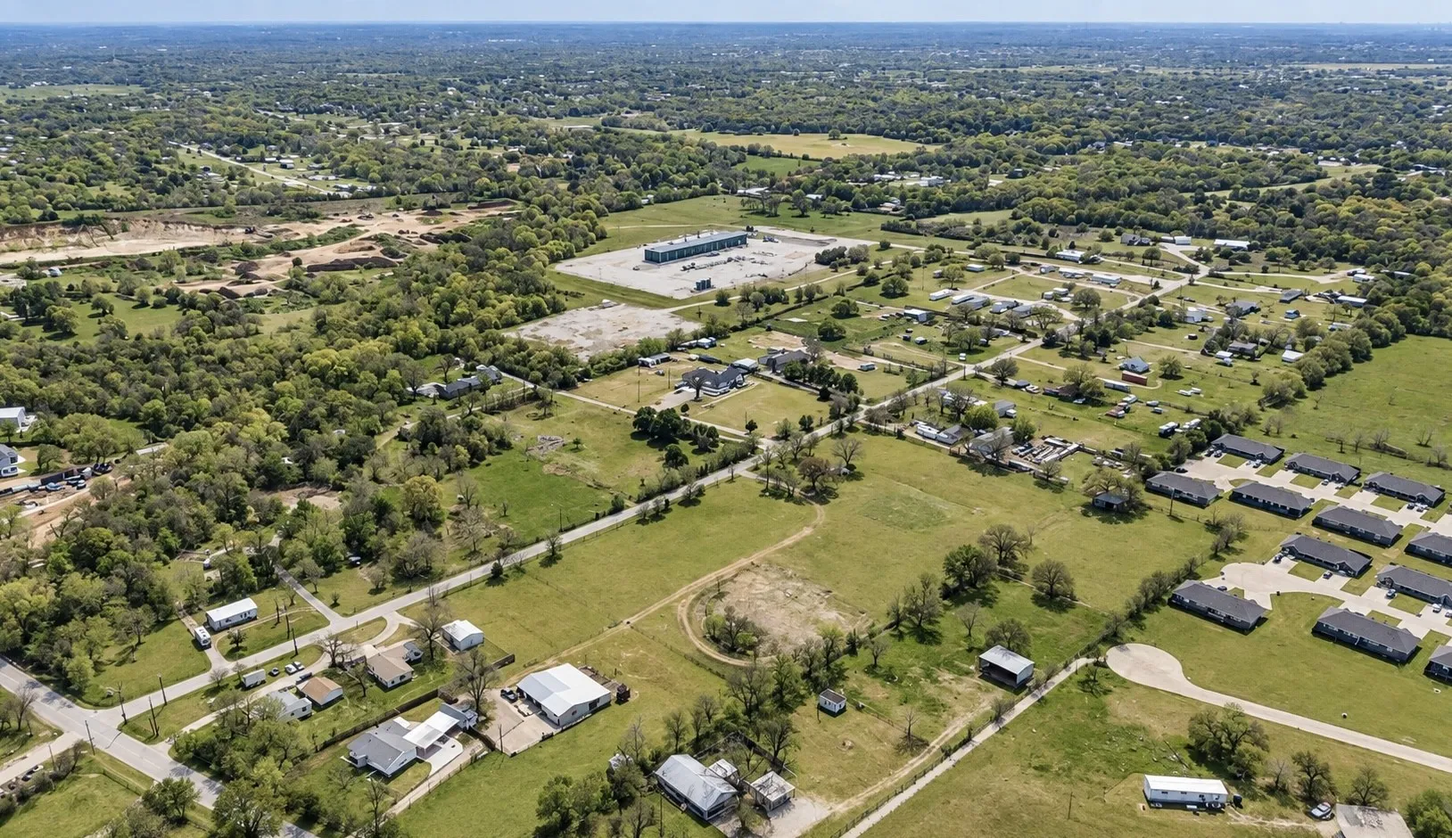 Expansive aerial perspective showcasing varied land use, including established residential areas, commercial properties, and undeveloped green spaces