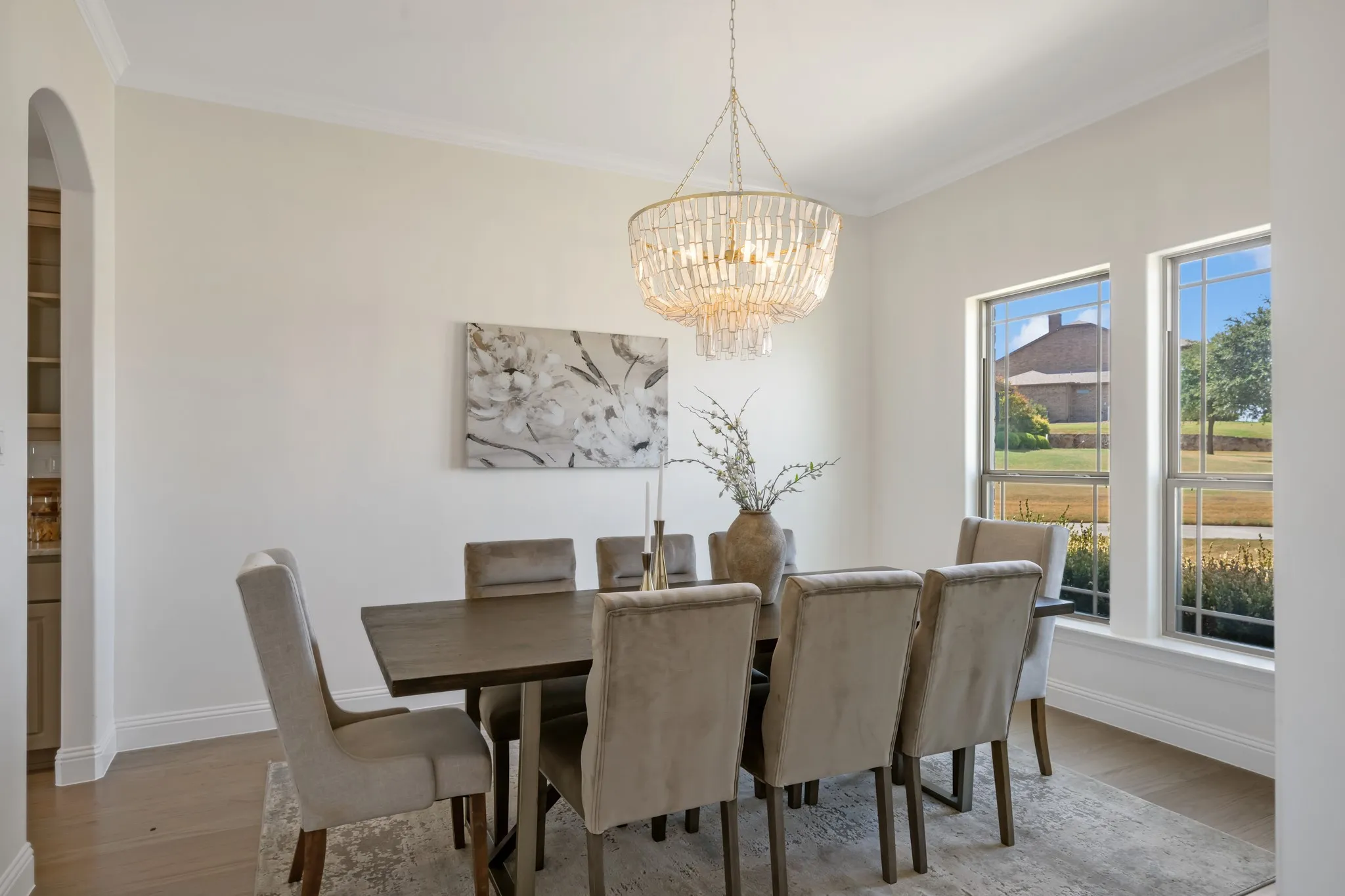 Formal dining space featuring crown molding, two large windows, a decorative chandelier, and light wood-finish flooring