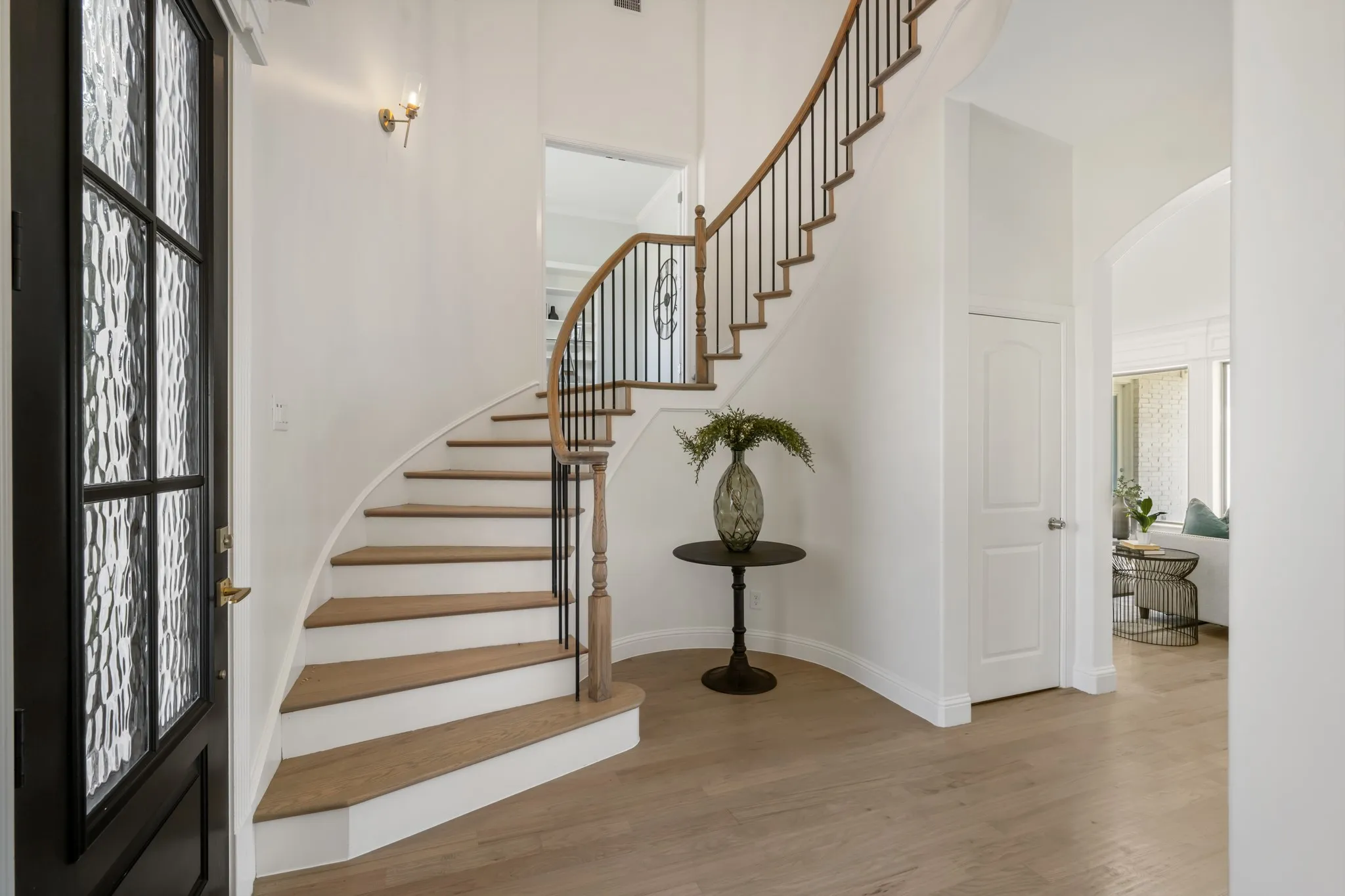 Curved staircase with wood-finish treads and wrought iron​​‌​​​​‌​​‌‌​‌‌​​​‌‌​‌​‌​‌​​​‌​​ balusters
