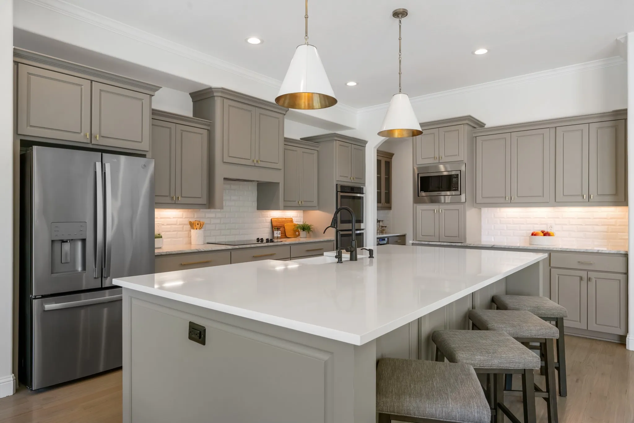 Kitchen featuring a large island with a white countertop, gray cabinetry, stainless steel appliances, and white subway tile backsplash
