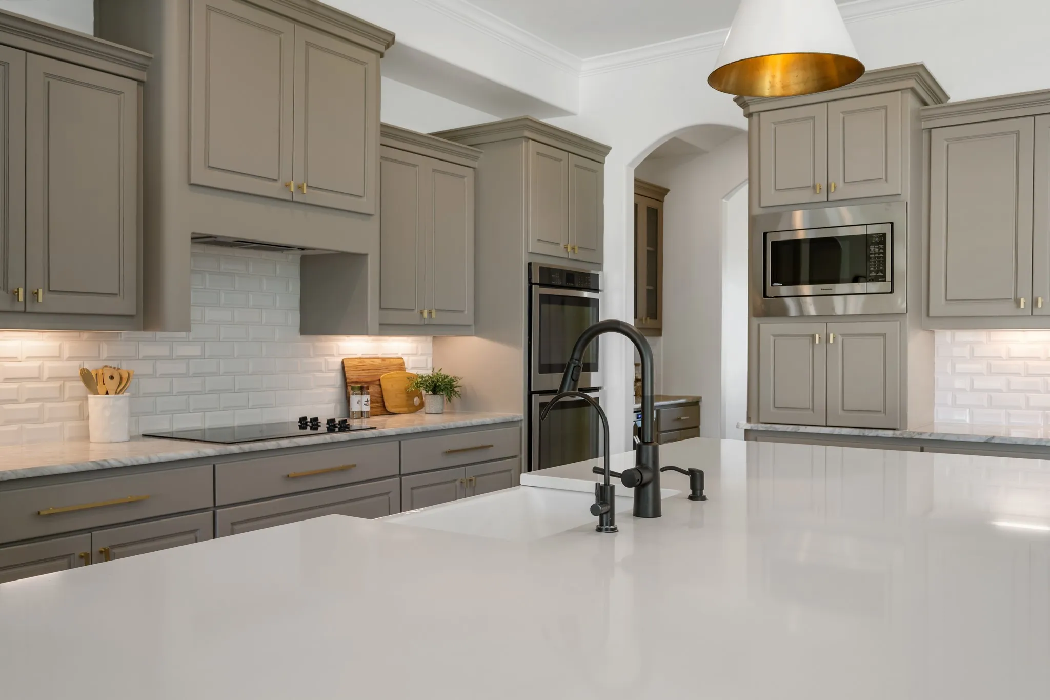 Spacious kitchen featuring gray shaker-style cabinetry, a large kitchen island with a built-in sink, stainless steel appliances, white subway tile backsplash, and recessed lighting