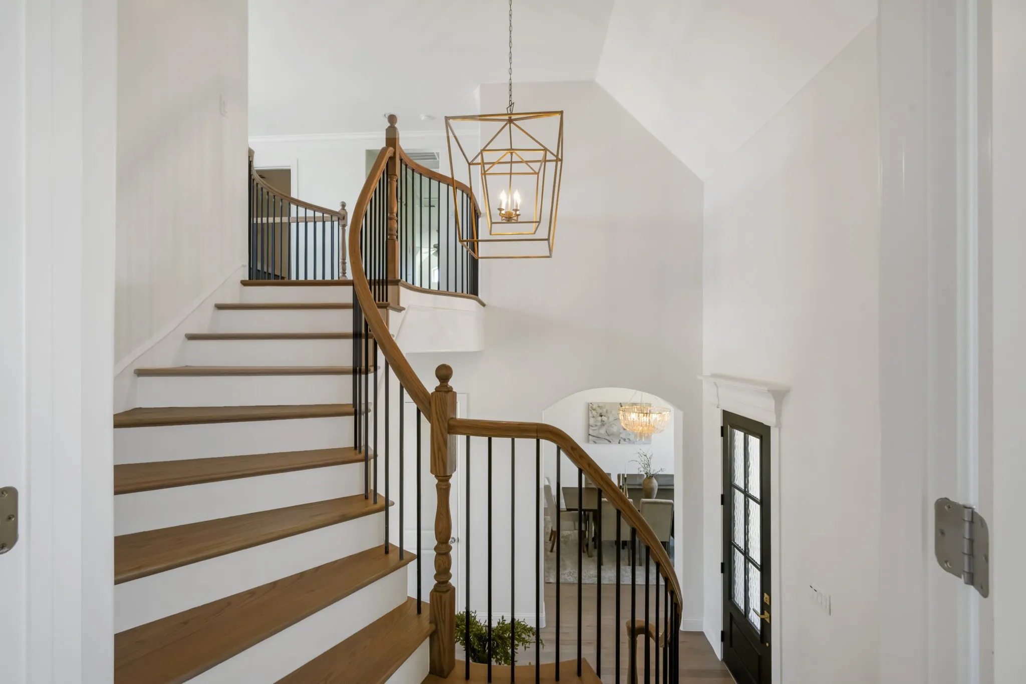 Curved staircase with wood-finish treads and black metal balusters