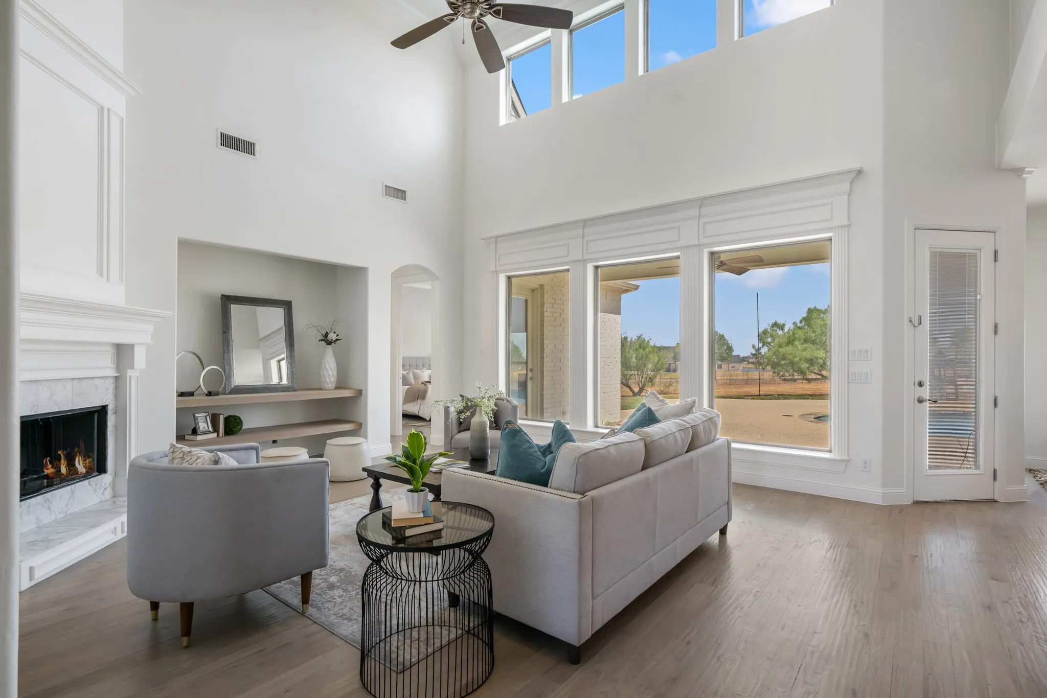 Vaulted ceiling, ceiling fan, large windows, wood-finish flooring, fireplace with marble surround