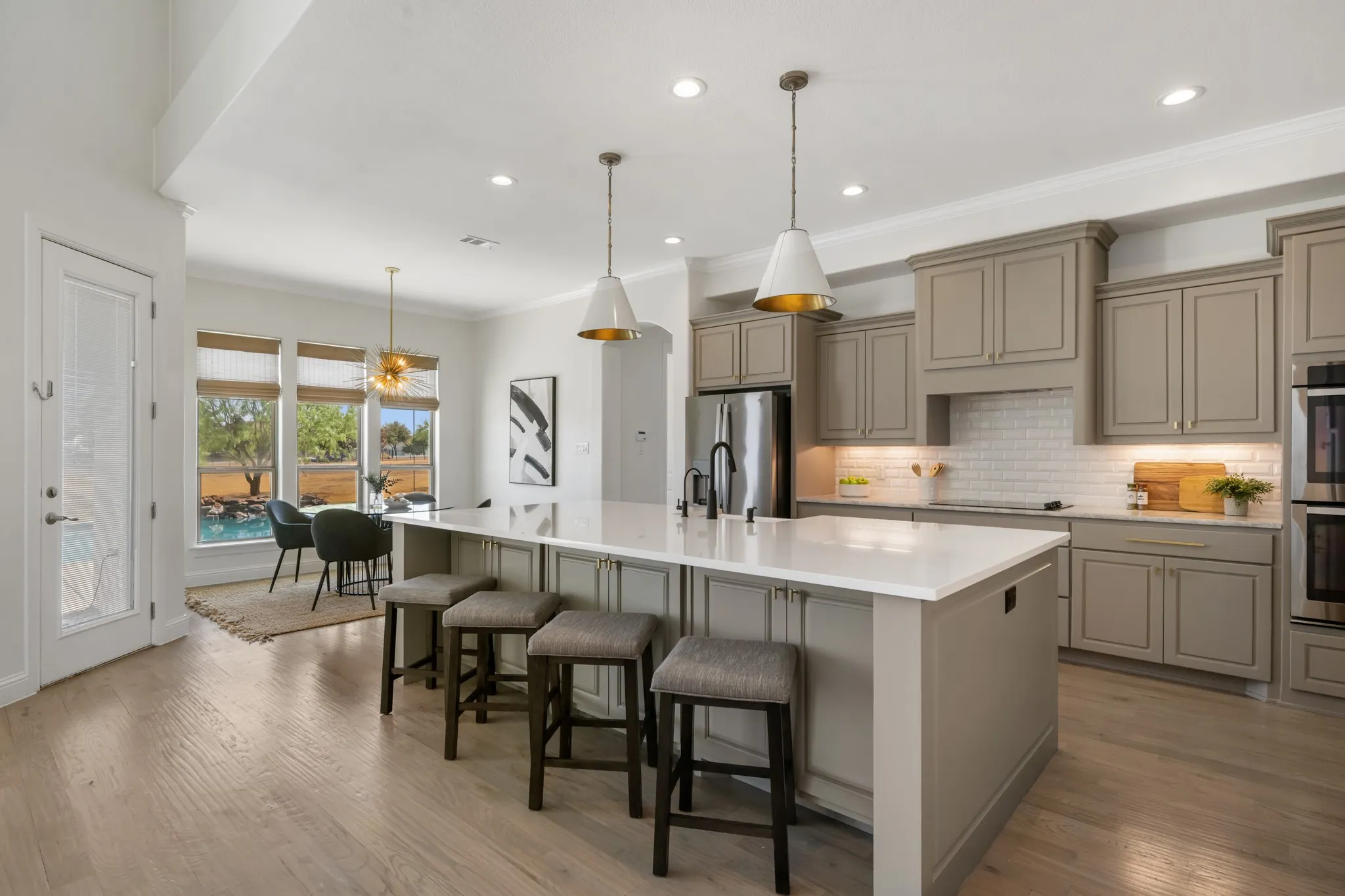 Kitchen with recessed lighting, wood-finish flooring, a central island with countertop seating, stainless steel appliances, and gray cabinetry