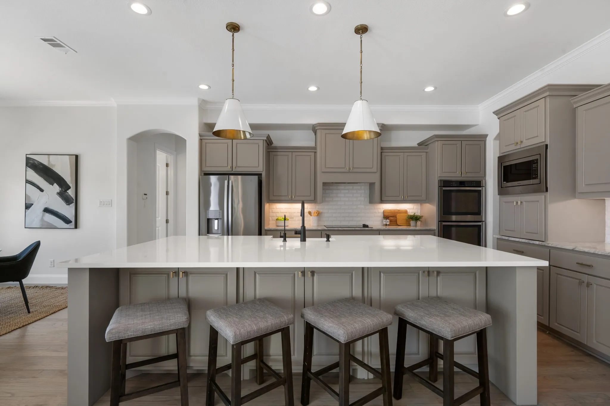 Kitchen featuring a large central island with seating, white countertops, built-in stainless steel appliances, grey cabinetry, and recessed lighting