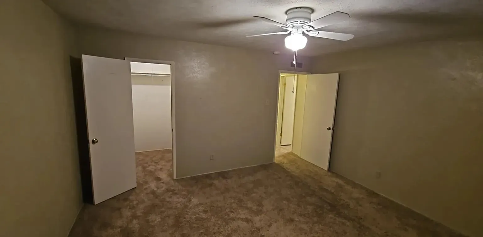 Carpeted room featuring a ceiling fan with light fixture and a closet with bifold doors
