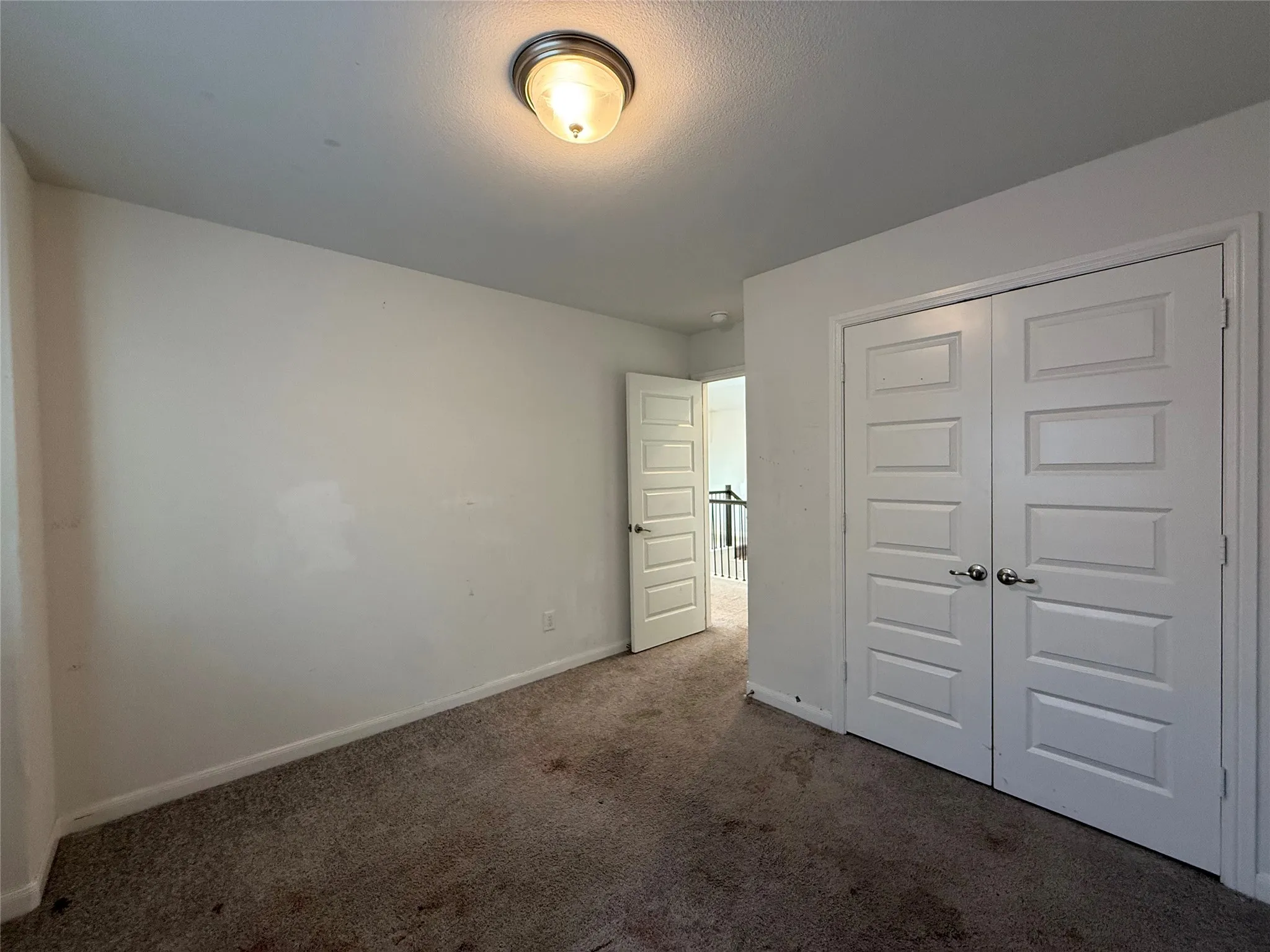Recessed panel bi-fold doors, flush mount ceiling light fixture, wall-to-wall carpeting