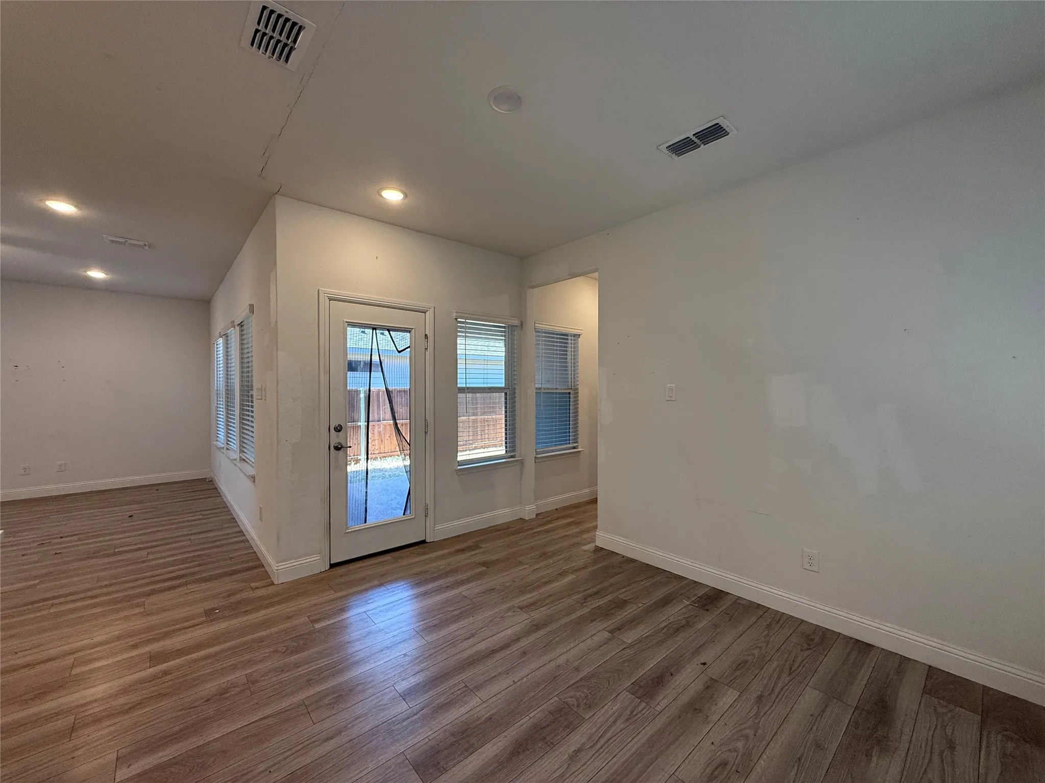 Wood-finish flooring throughout, recessed lighting, and multiple windows with blinds