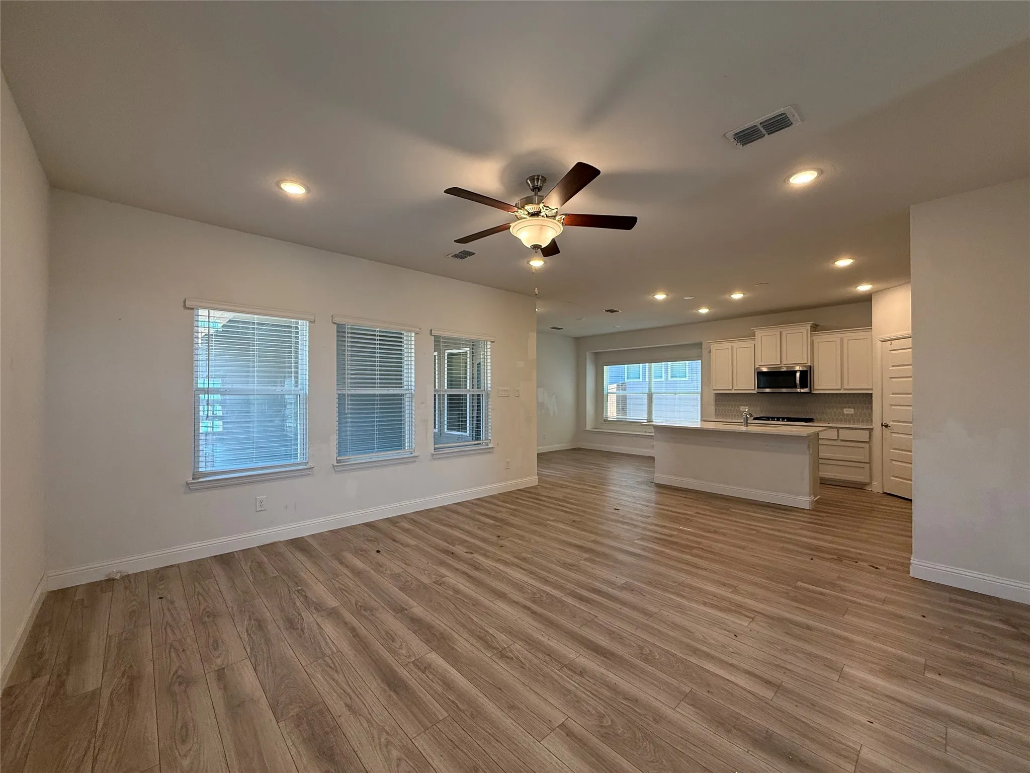 Open-concept living area with wood-finish flooring, recessed lighting, and a ceiling fan