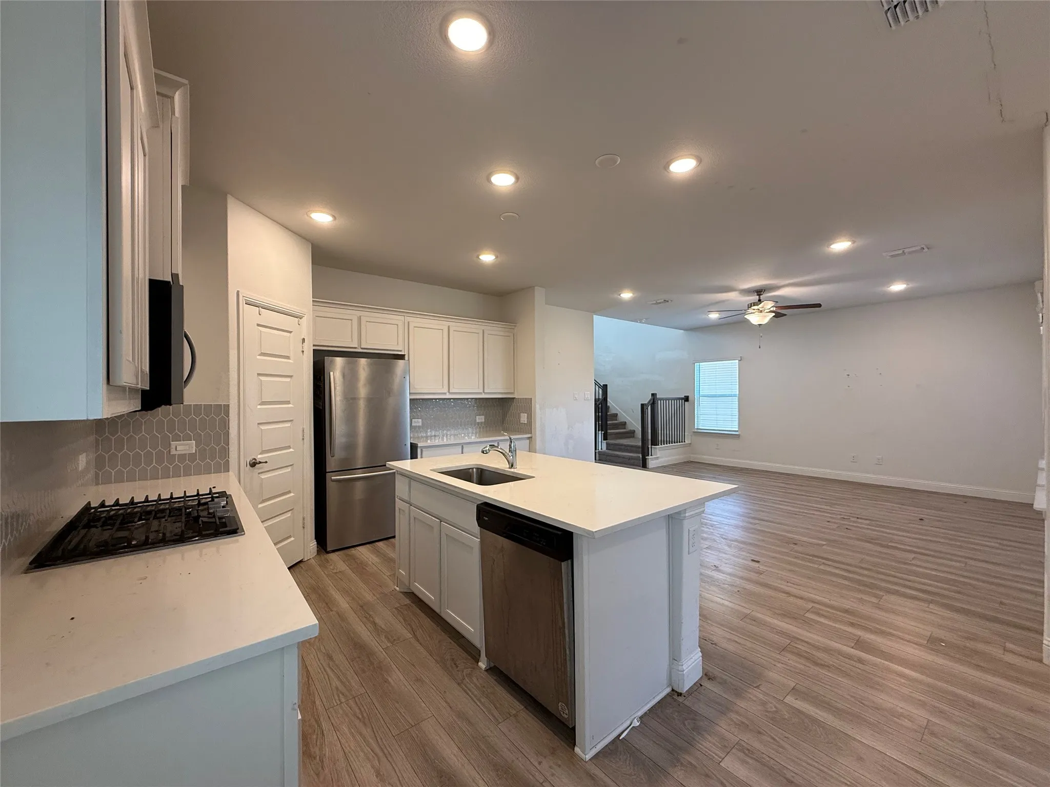 Kitchen featuring white cabinetry, stainless steel appliances, recessed lighting, and a center island with a sink