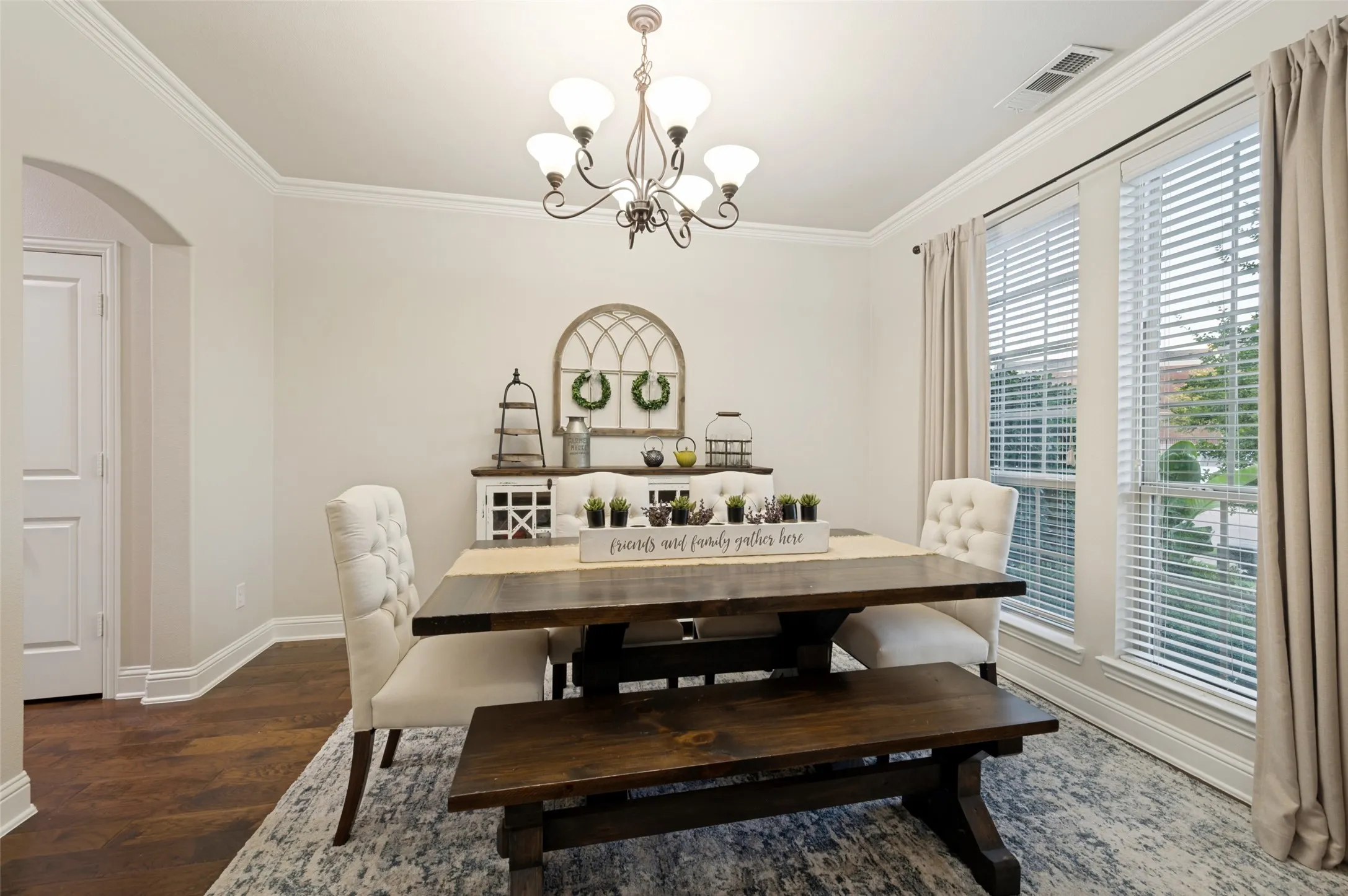 Elegant formal dining room featuring a classic chandelier, crown molding, and large windows that fill the space with abundant natural light, creating the perfect setting for everyday meals or special occasions.